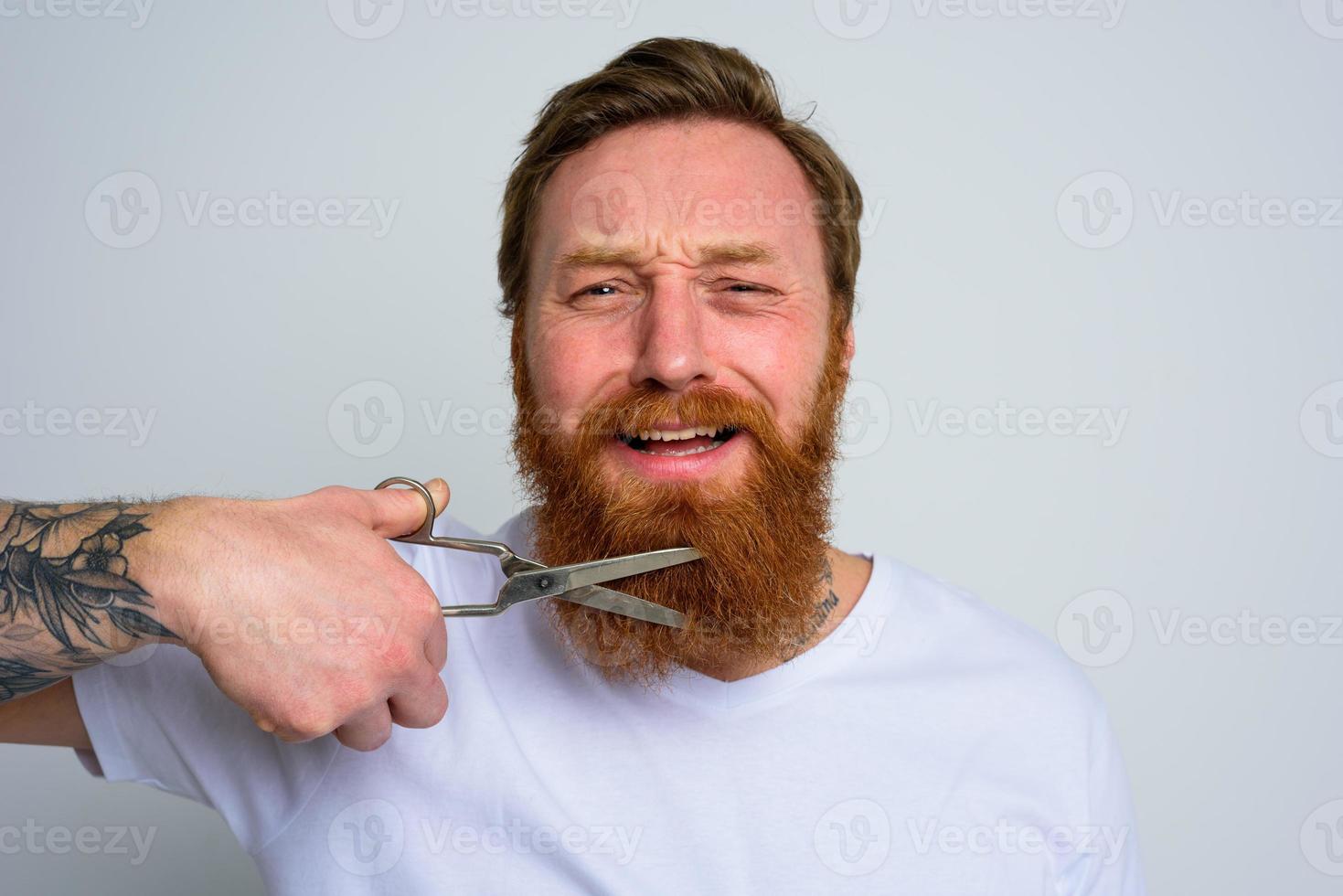 infeliz hombre con tijeras Doees no querer a cortar el barba foto