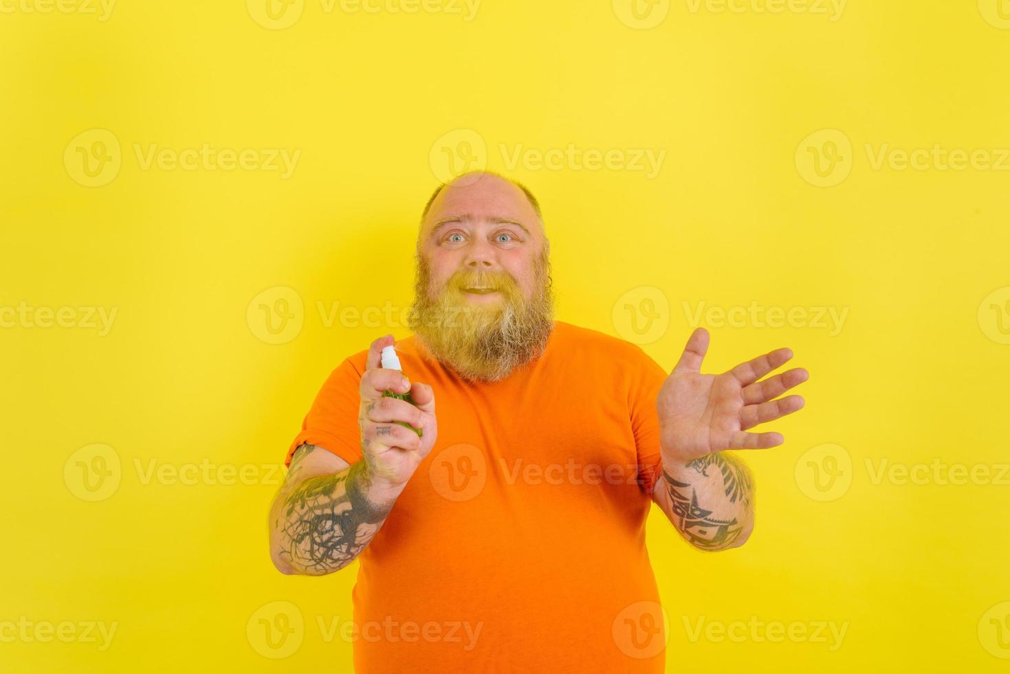 Happy man with beard and tattoos holds a hands cleaner against covid19 photo