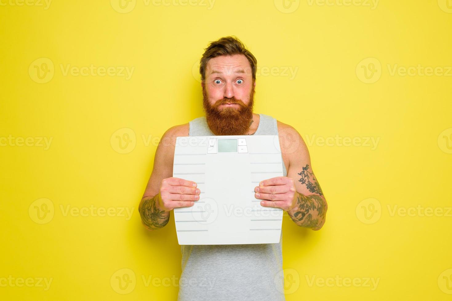 Man with beard and tattoos holds an electronic balance photo