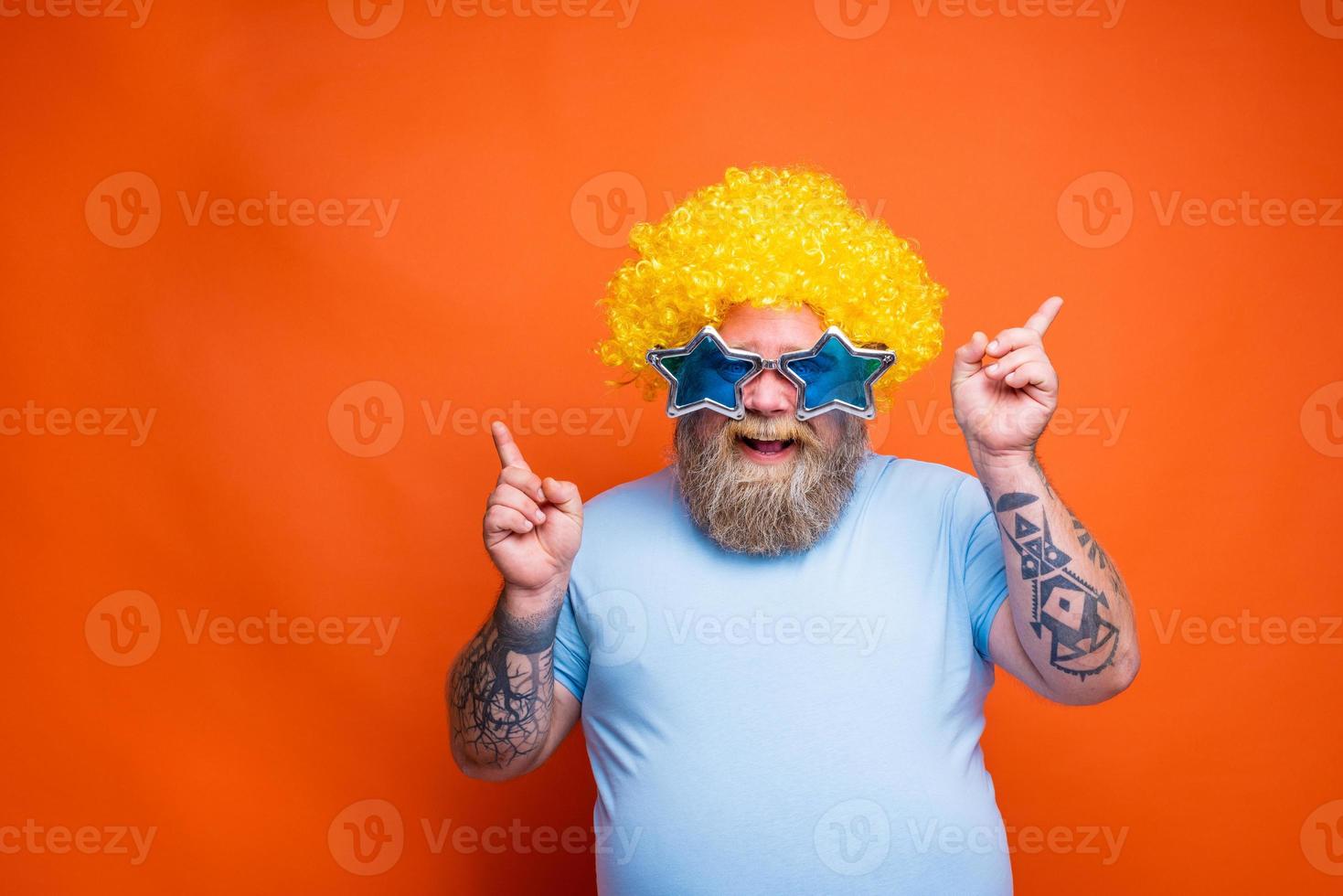 Fat happy man with beard, tattoos and sunglasses dances music on a disco photo