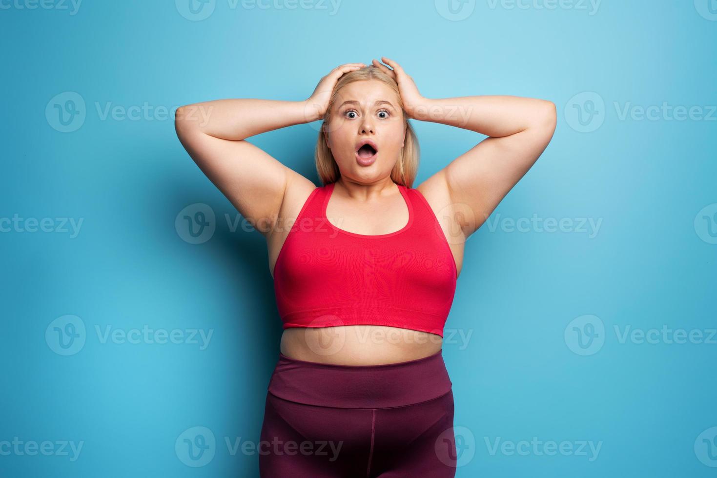 Fat girl is worried because the scale marks a high weight. Cyan background  20626240 Stock Photo at Vecteezy