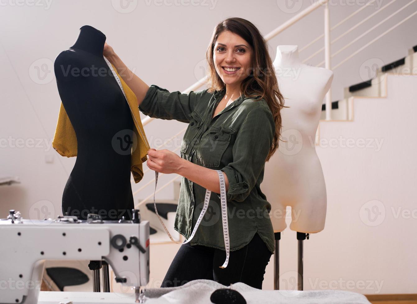 Seamstress works to new clothes commissioned by a client in a shop photo