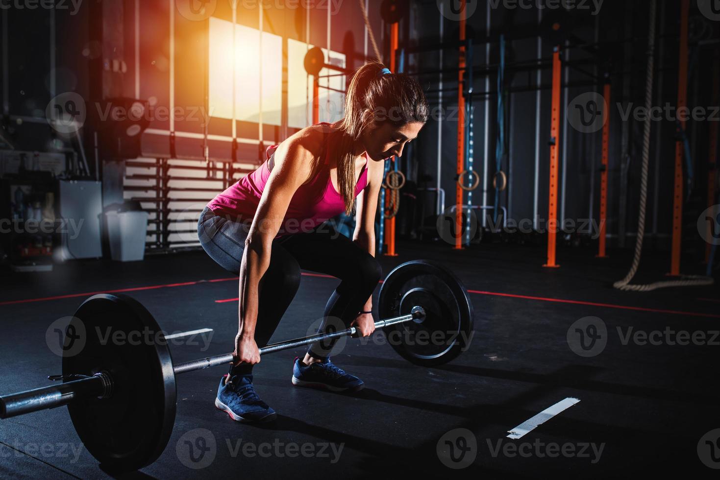 Athletic girl works out at the gym with a barbell photo