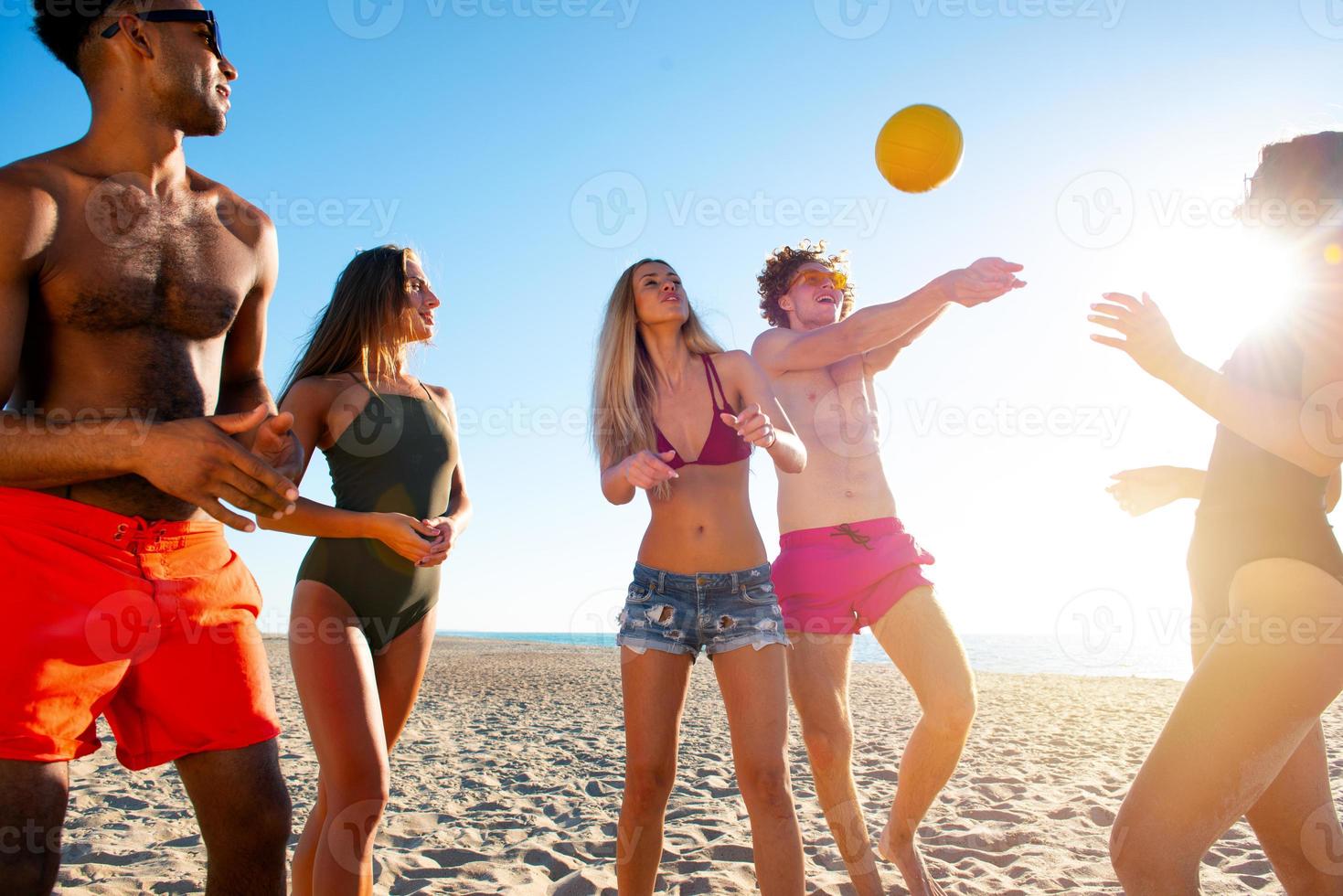 Group of friends playing at beach volley at the beach photo