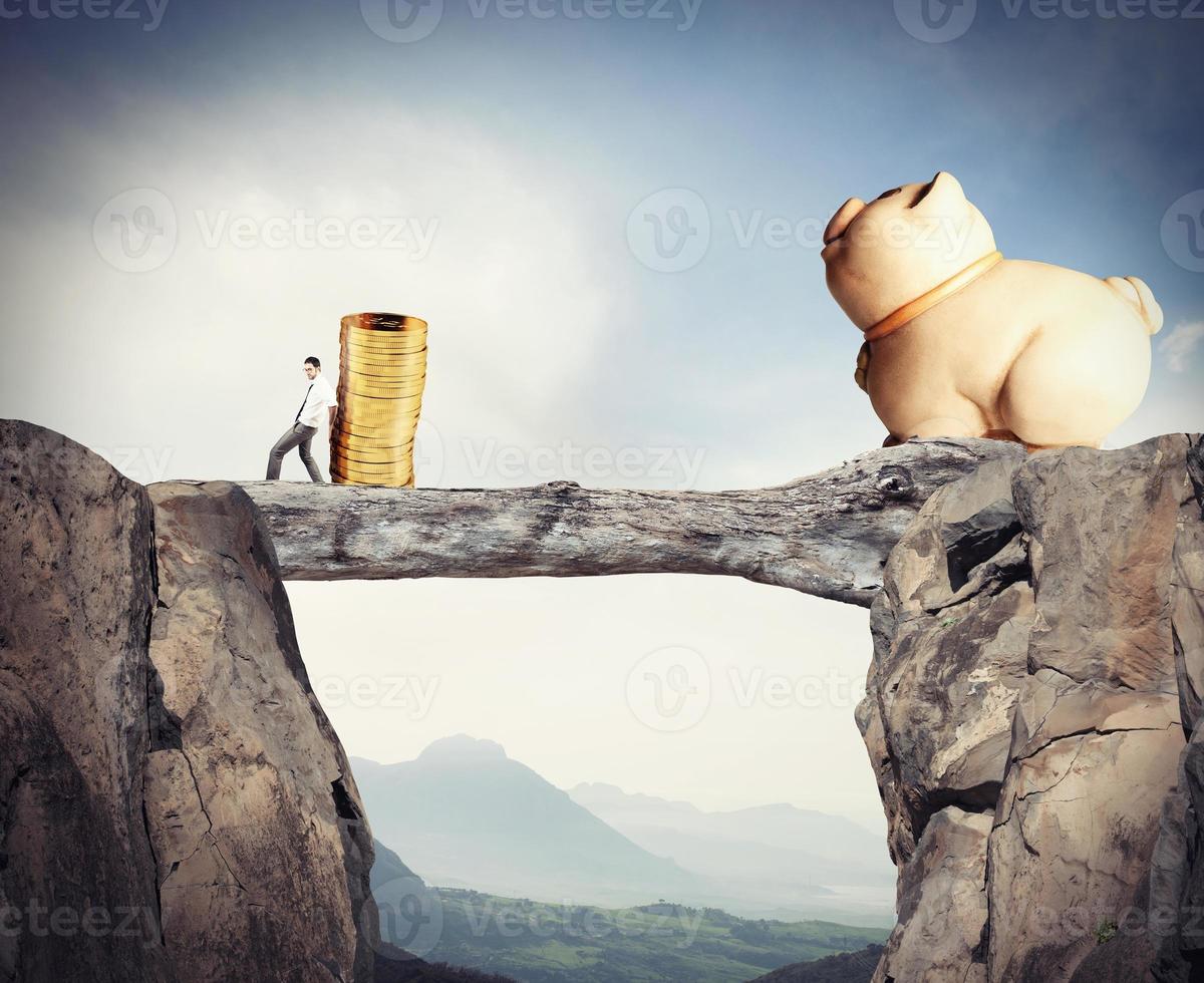 Businessman moves a pile of coins to a moneybox. concept of difficulty to saving money photo