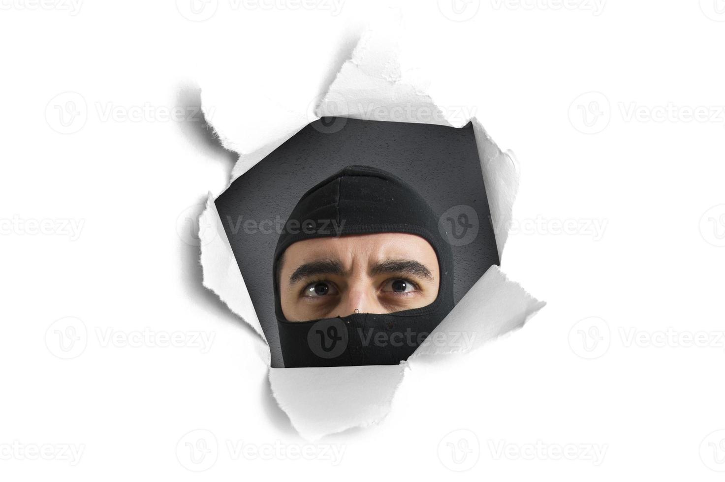 Thief looking through a paper hole photo