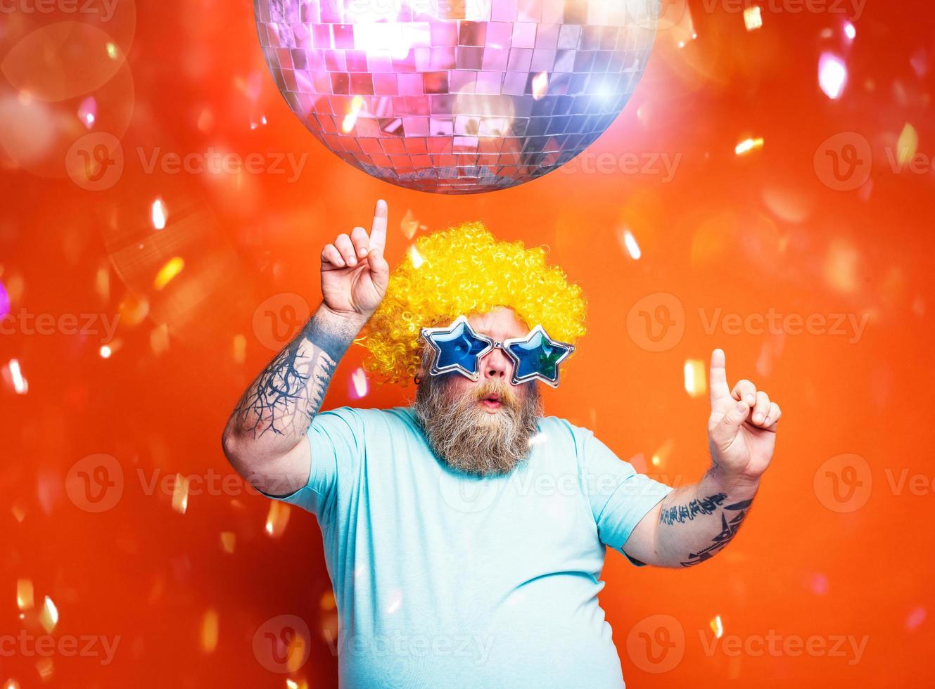 grasa hombre con barba, tatuajes y Gafas de sol bailes música en un disco foto