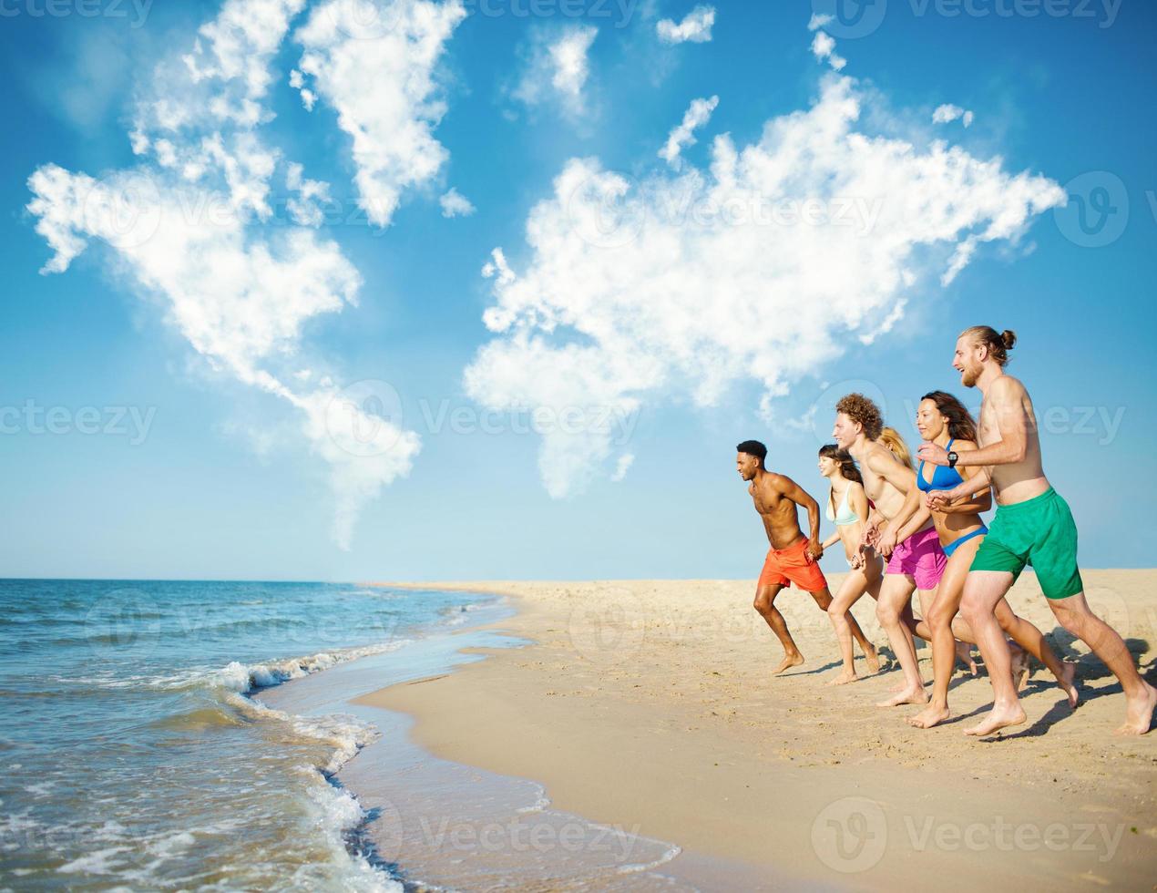 Group of friends run in the sea with world map made of clouds. Concept of summertime photo