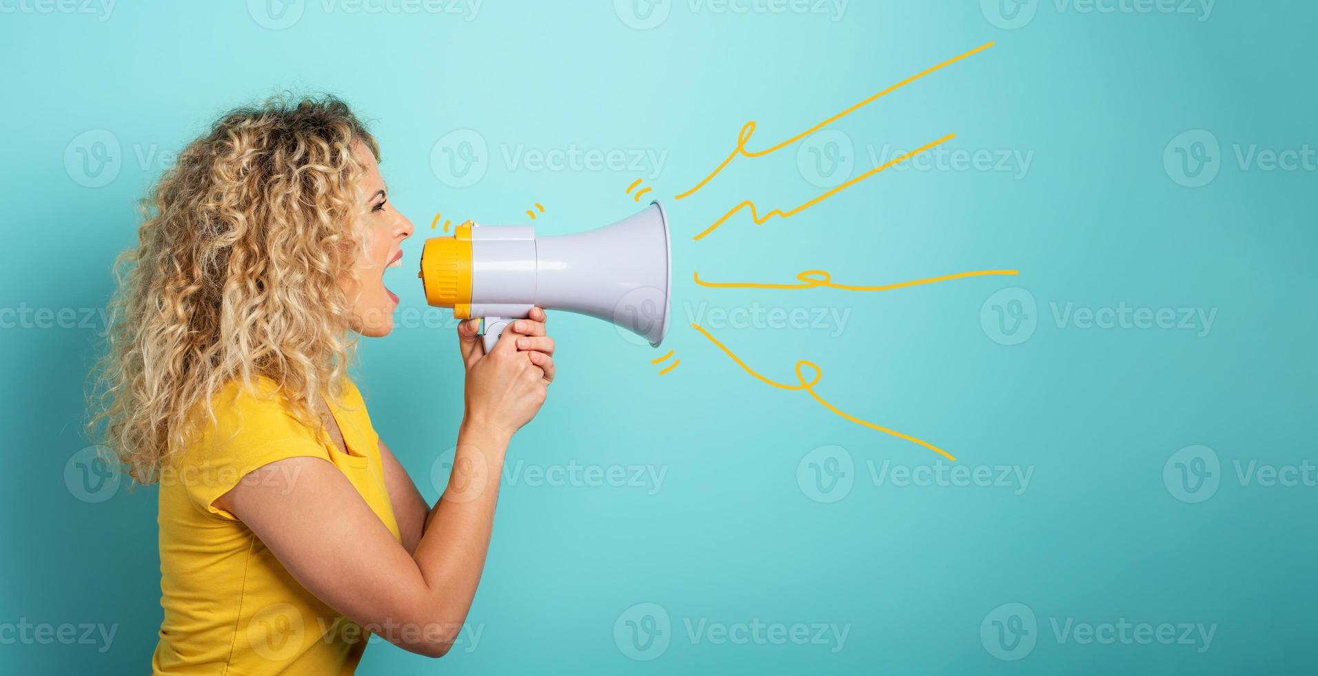 Woman screams with loudspeaker. angry expression. cyan background photo