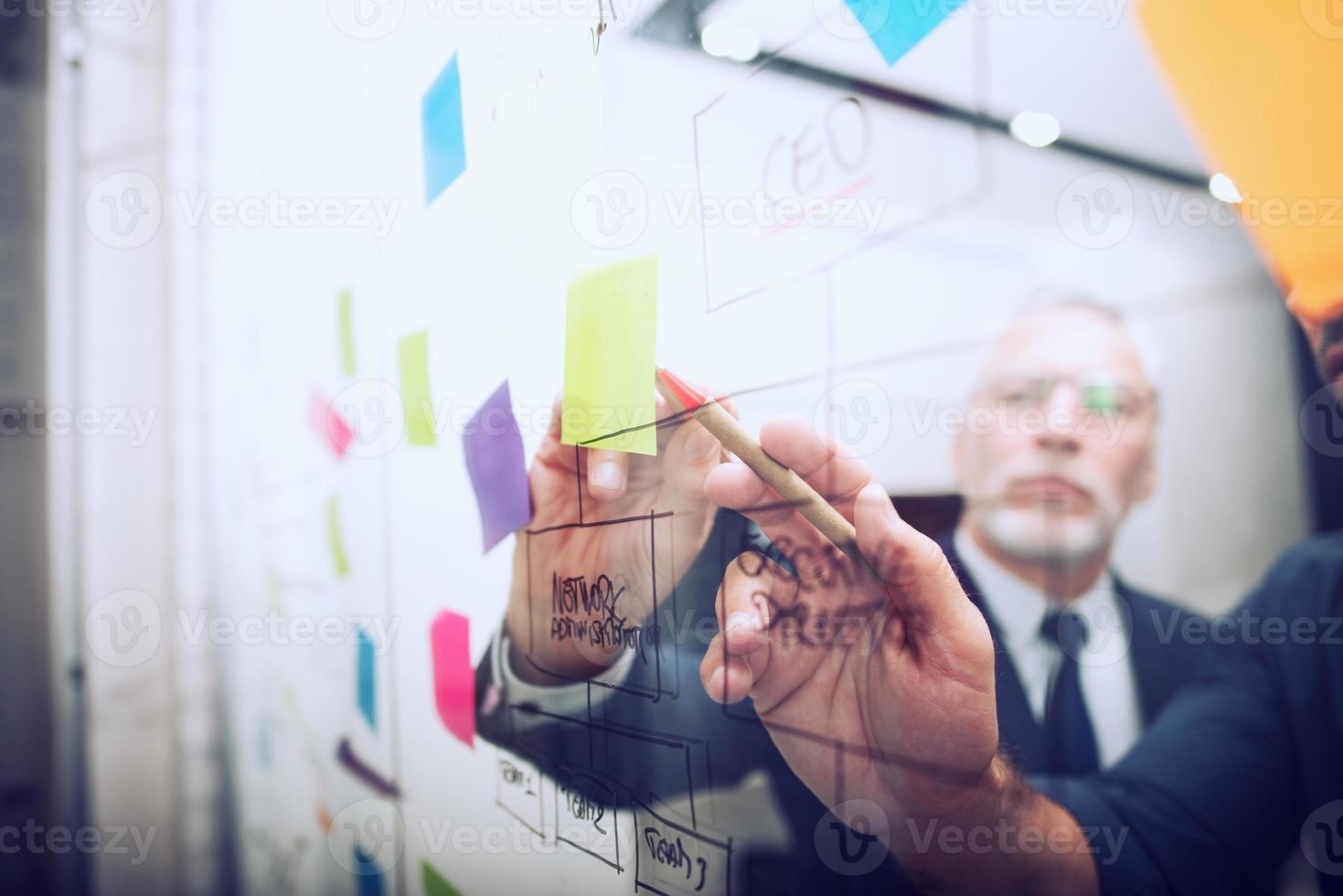 Business people work together drawing a business diagram with marking pen. concept of teamwork, partnership and success photo
