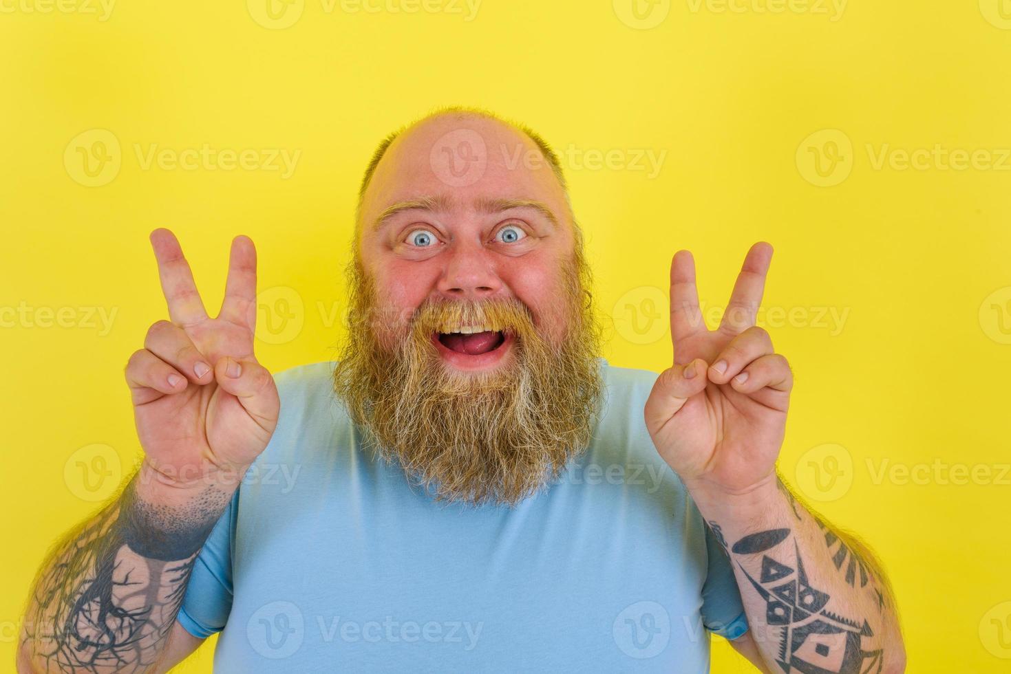 Happy man with beard and tattoos does winning gesture photo