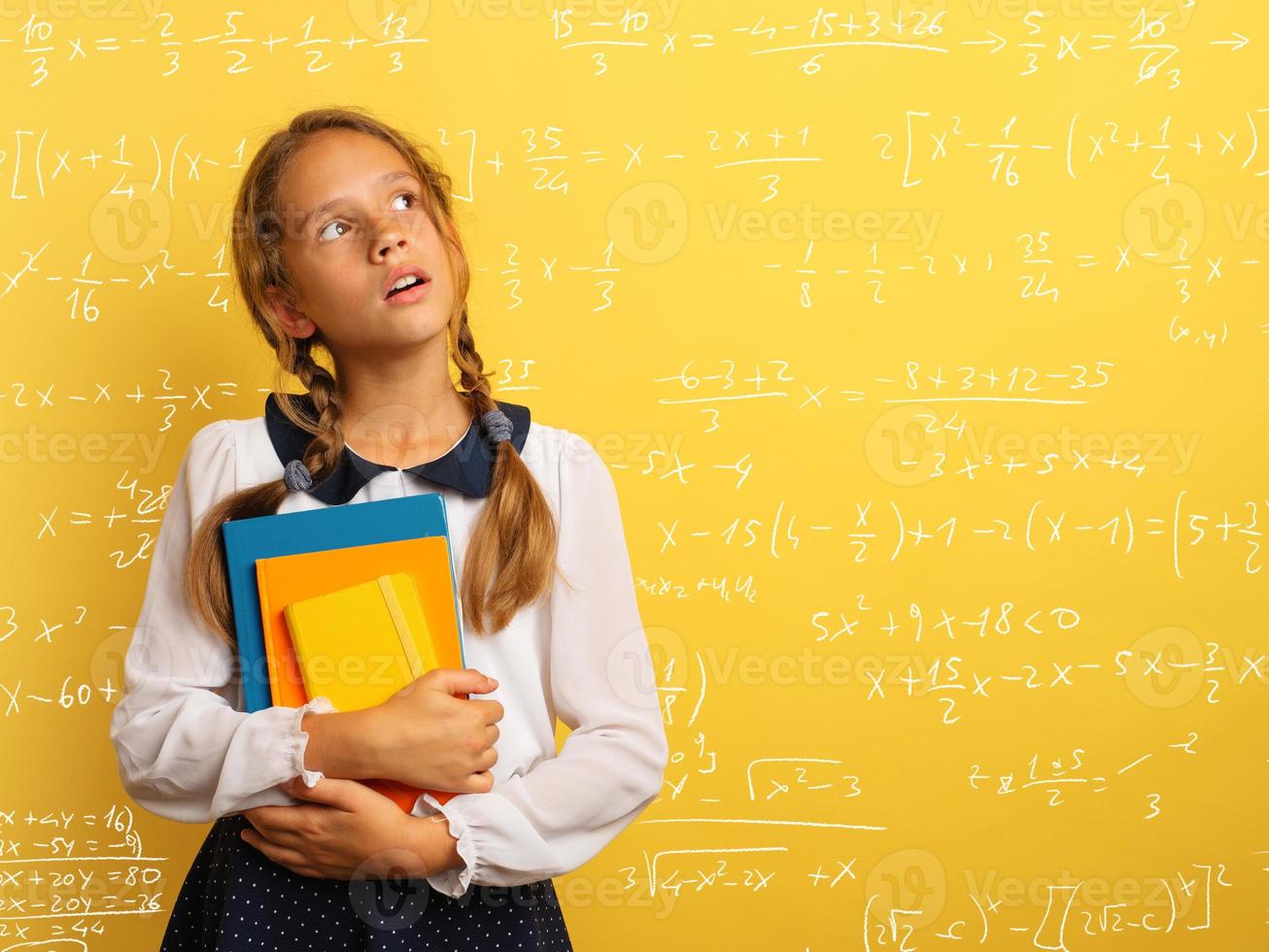 Young student is with shocked expression and think about complex exercises. Yellow background photo