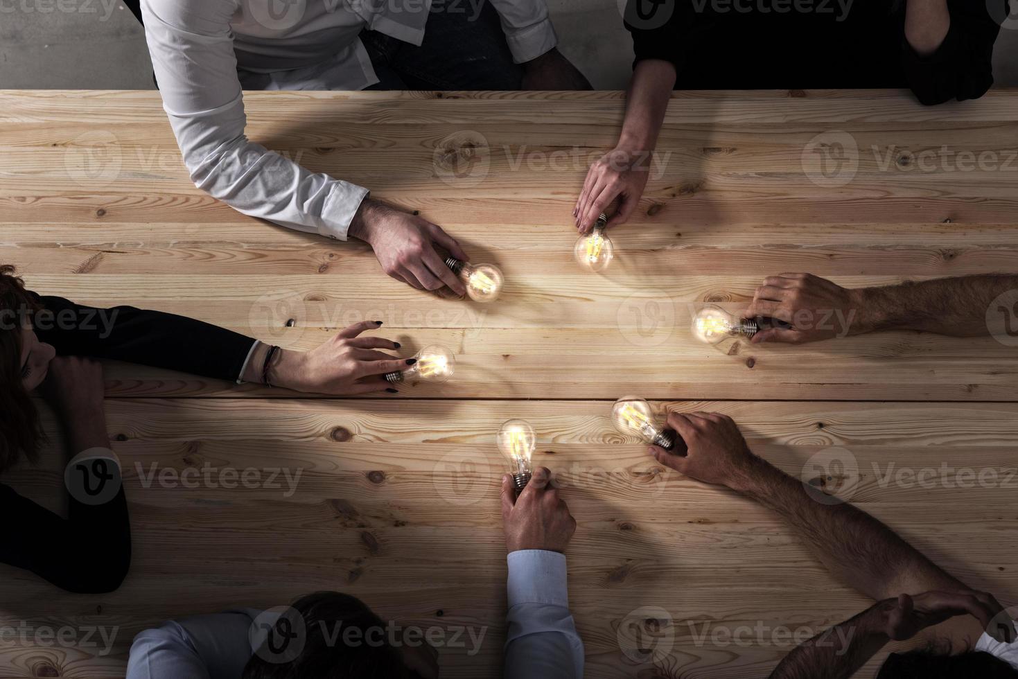 Teamwork and brainstorming concept with businessmen that share an idea with a lamp. Concept of startup photo