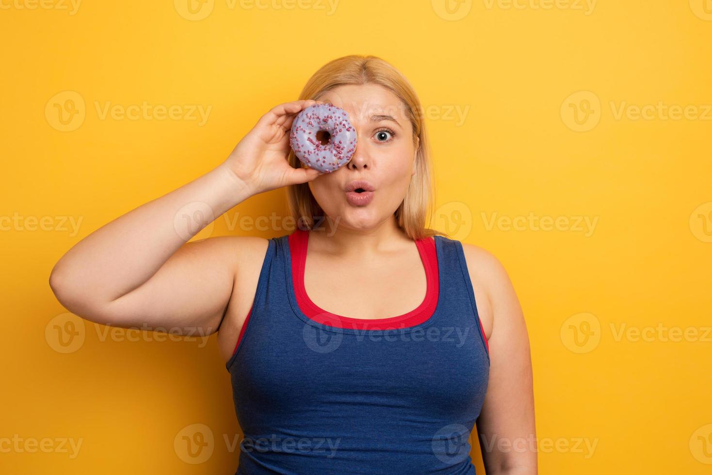 Fat girl eats sweet instead of do gym. Cyan background photo