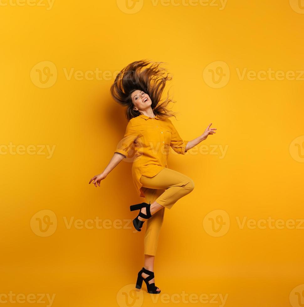 Brunette girl with a yellow clothes jumps. concept of fashion and shopping with joyful expression photo