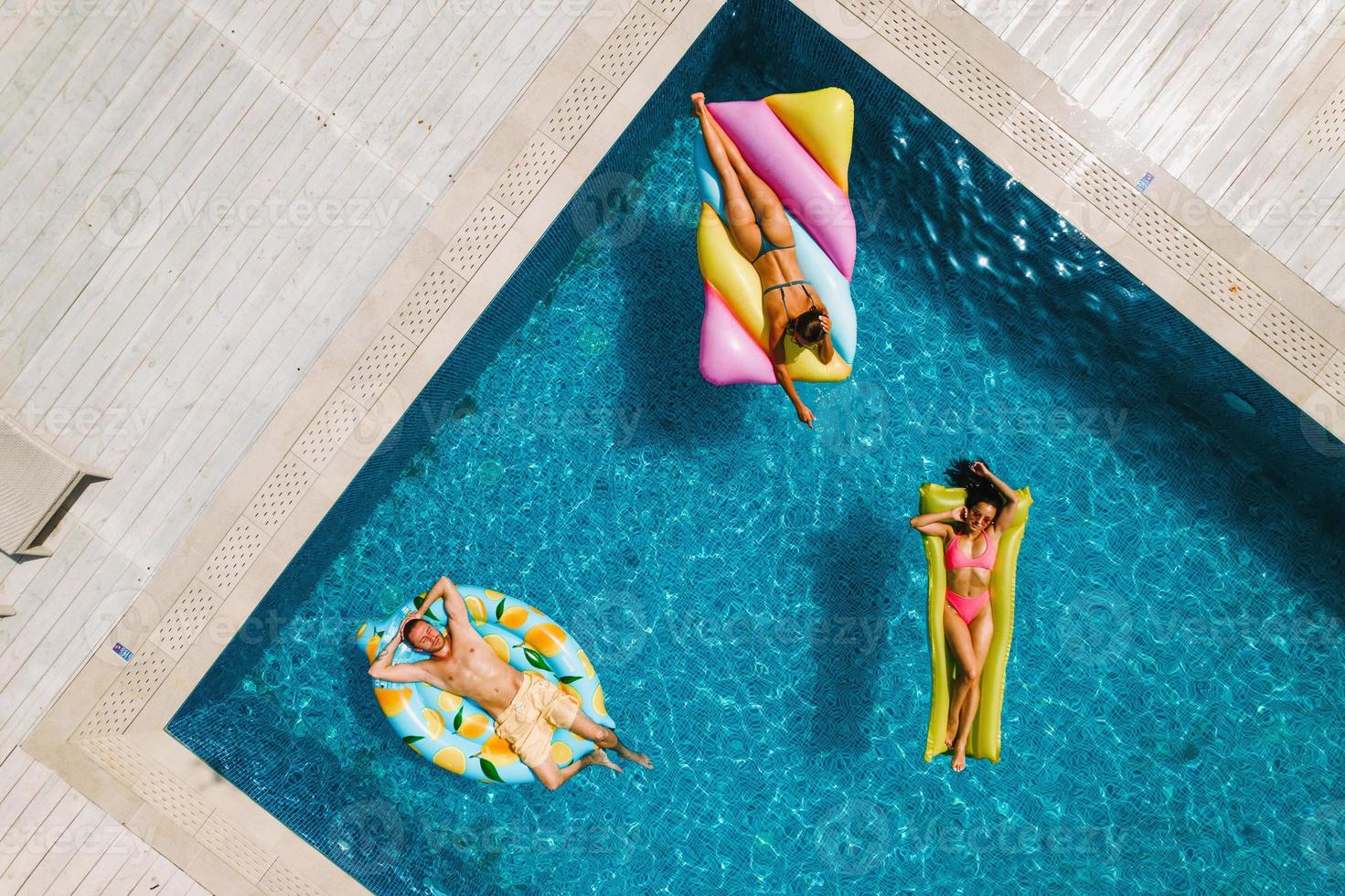 Friends in swimsuit in the pool getting a tan photo