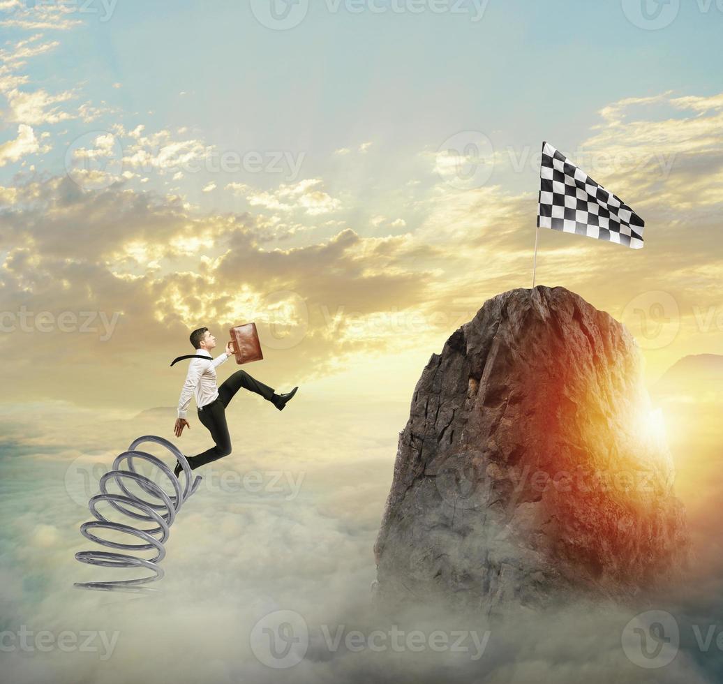 Businessman jumping on a spring to reach the flag. Achievement business goal and Difficult career concept photo