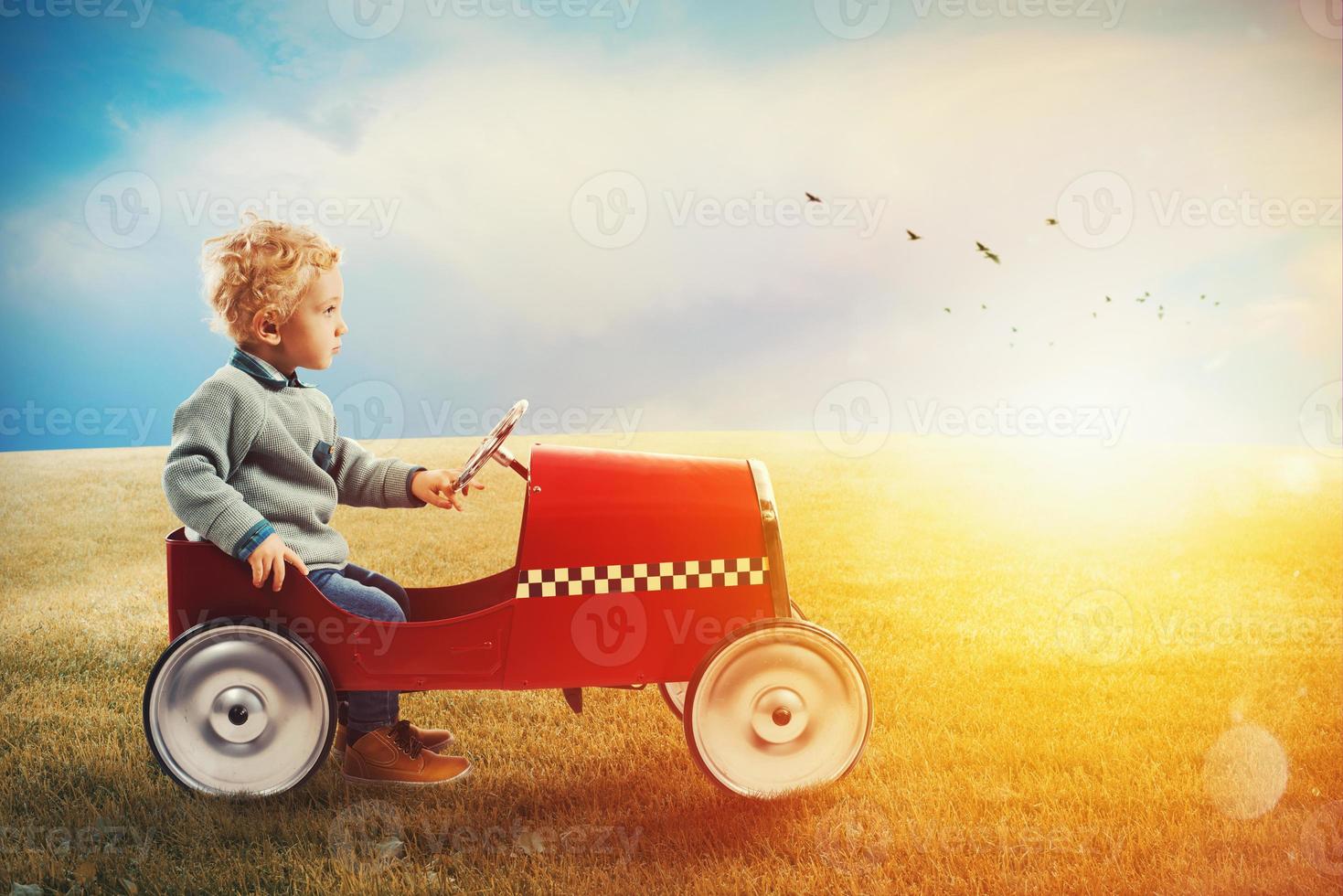 Child with car plays in a green field photo