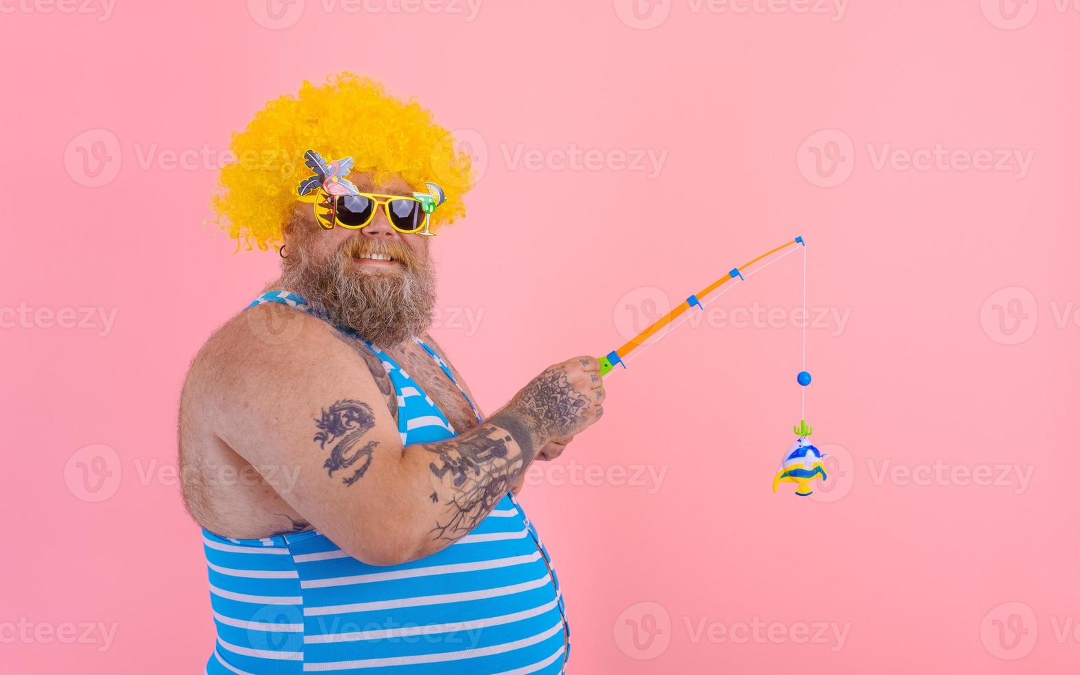 Fat happy man with beard and sunglasses have fun with the fishing pole photo