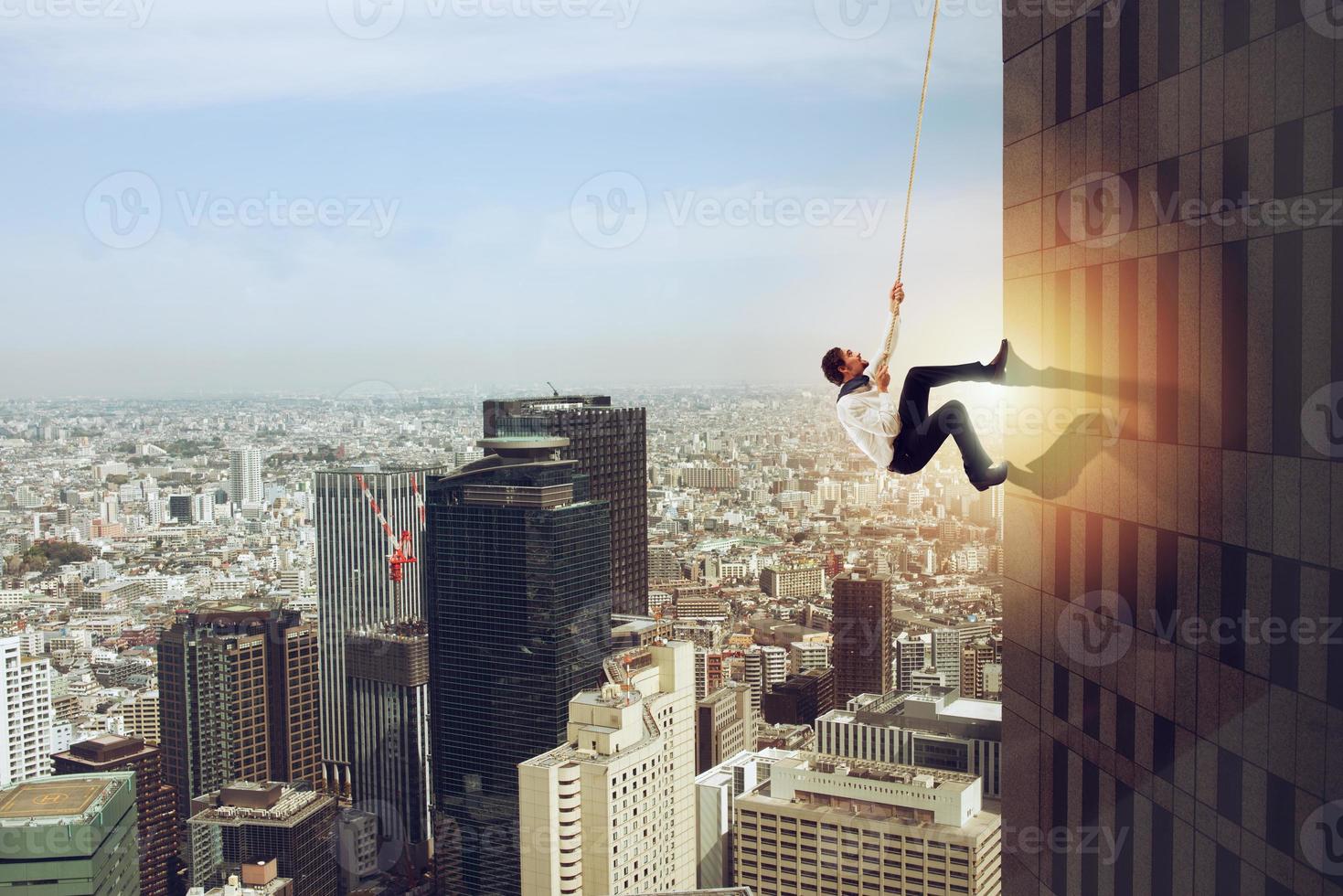 Businessman climbs a building with a rope. Concept of determination photo