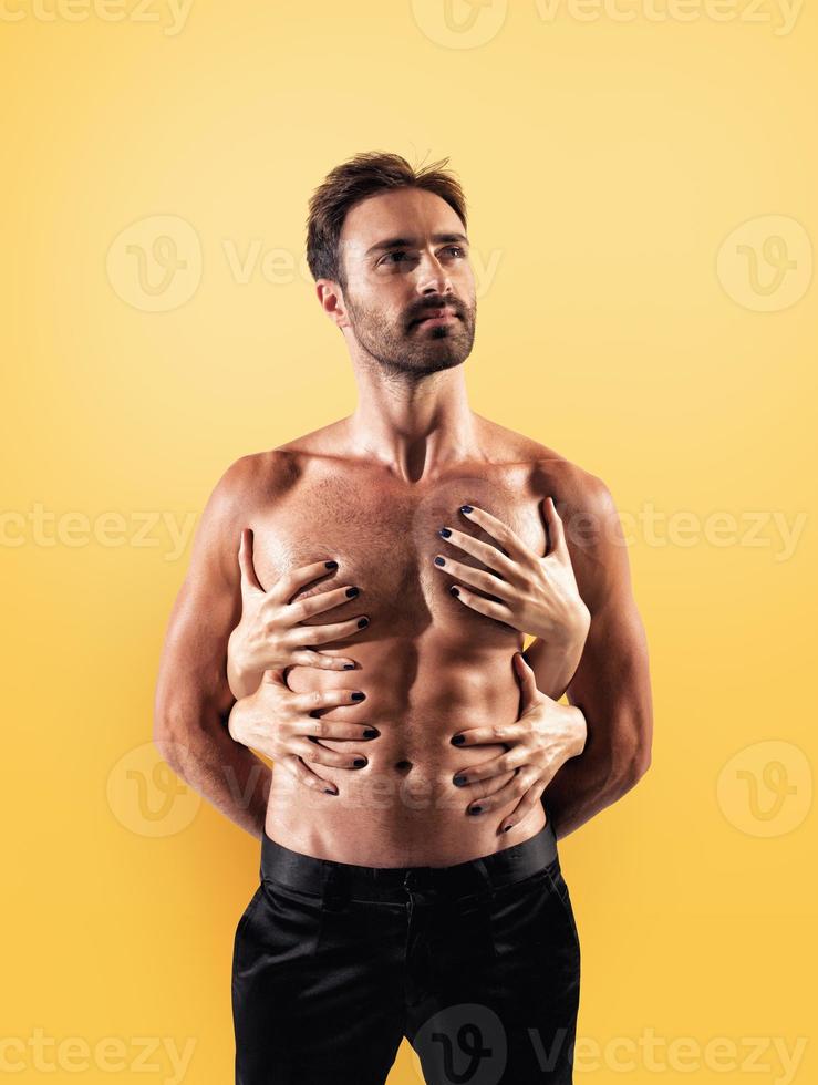 Sexy man touched by multiple woman hands photo