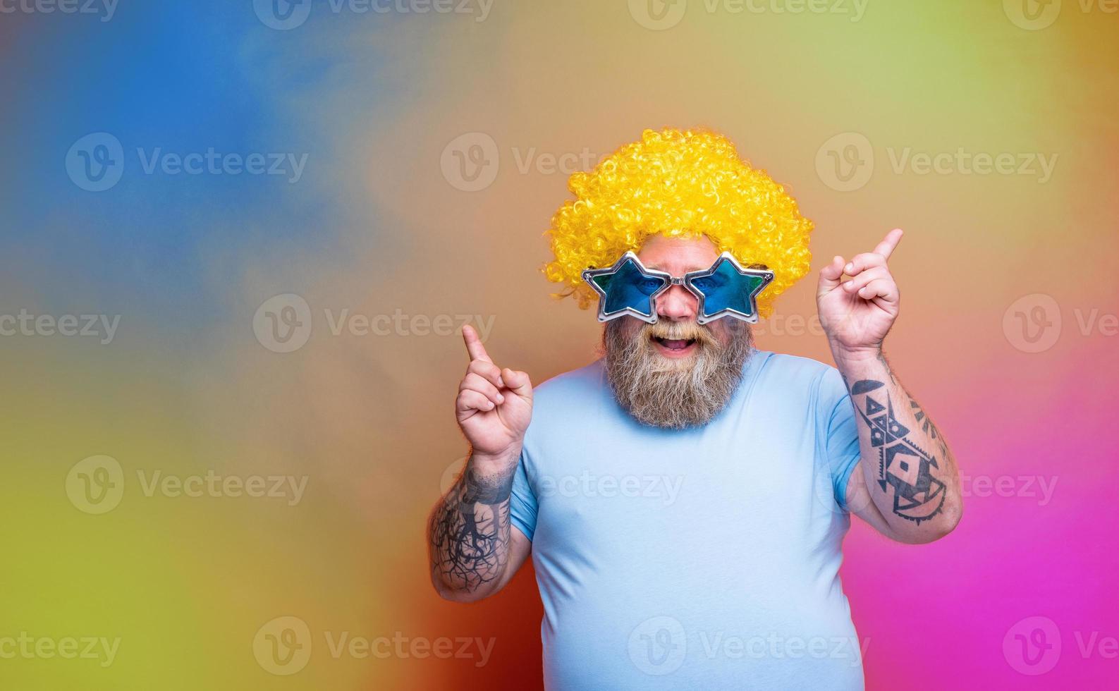 Fat happy man with beard, tattoos and sunglasses dances music on a disco photo