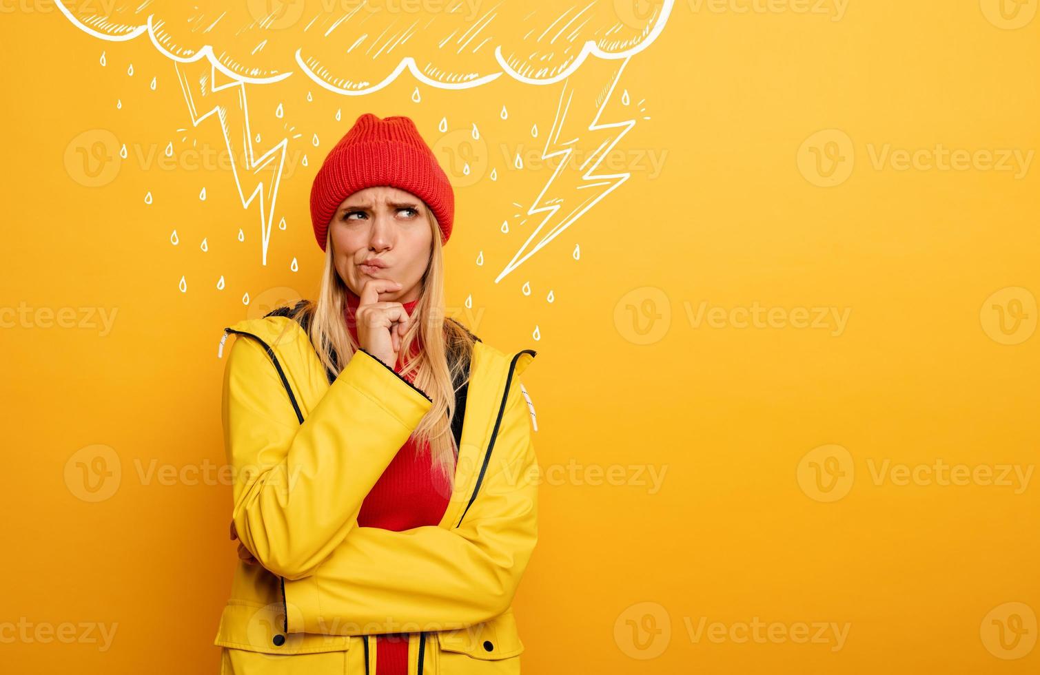 Girl thinks about negative things. Cloud, rain and lightning above her. Confused and pensive expression. Yellow background photo