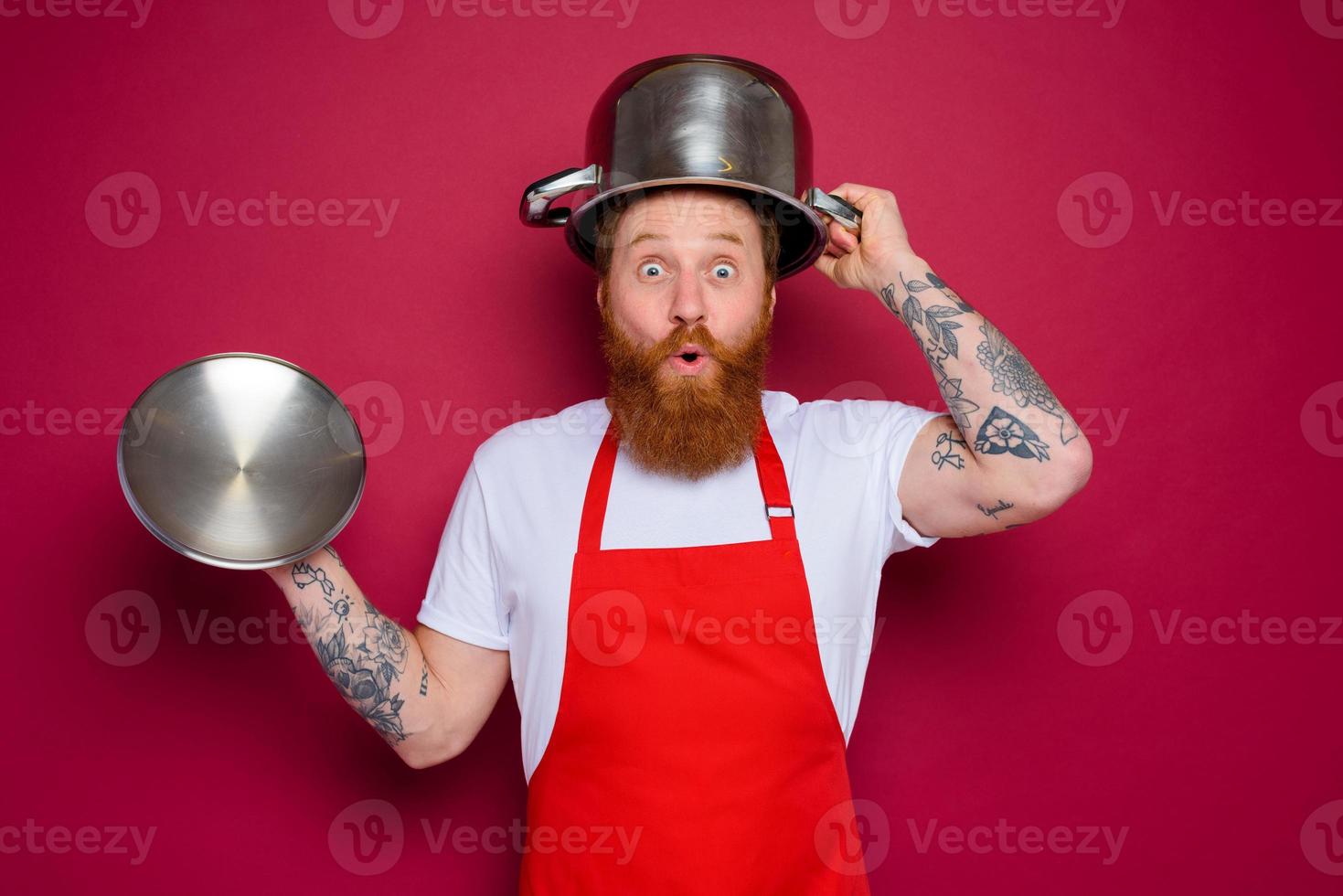 wondered chef with beard and red apron plays with pot photo