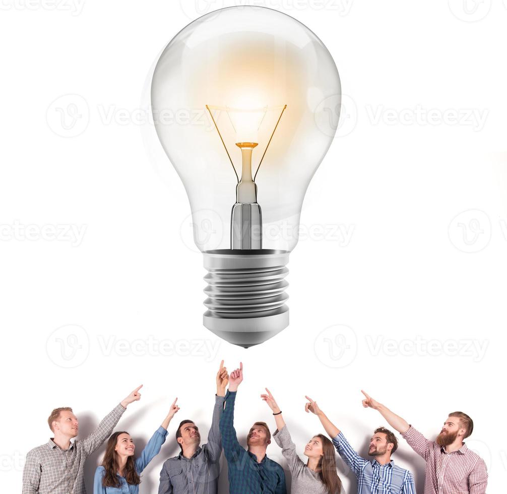 Brainstorming concept with businessmen that indicate an a lamp. Concept of idea and company startup photo