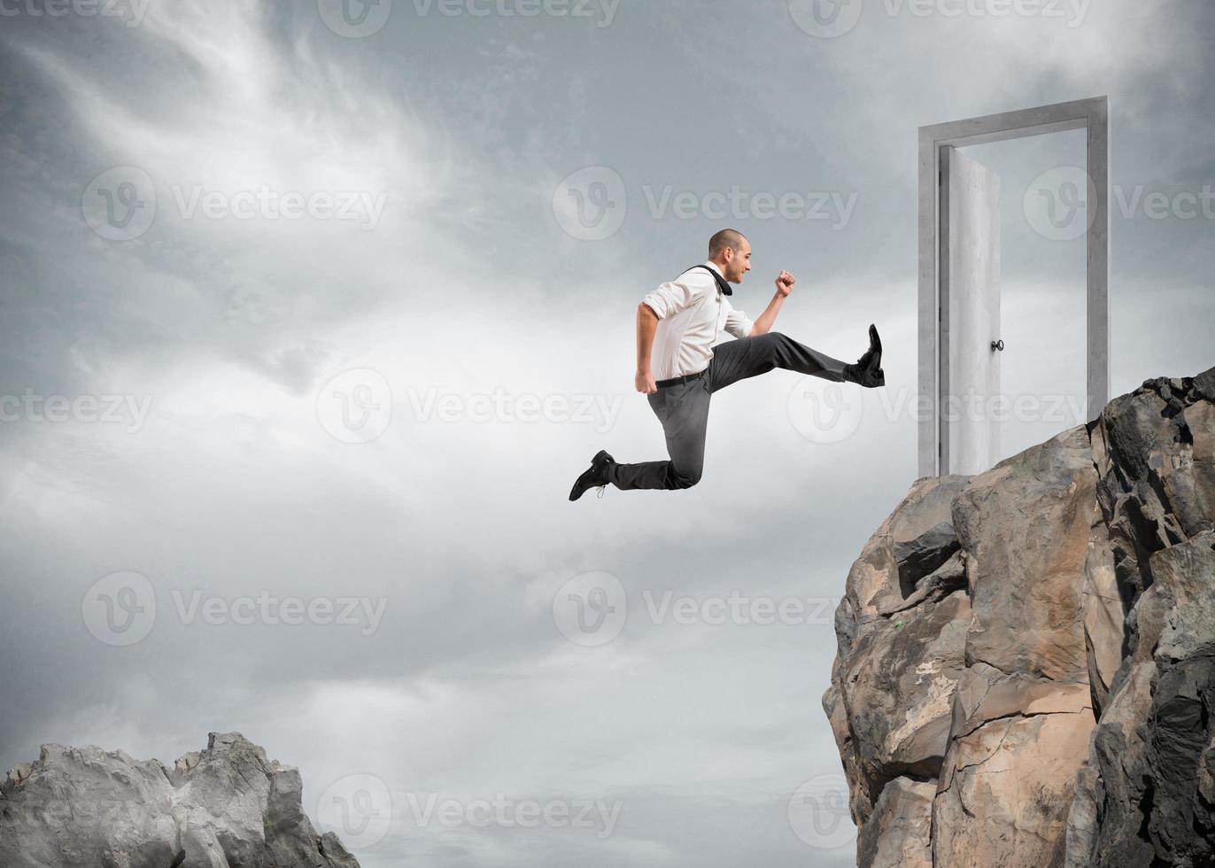 Businessman jumping over the mountains to reach a door photo