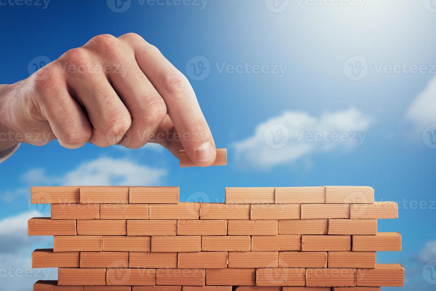 Businessman puts a brick to build a wall. Concept of new business, partnership, integration and startup photo