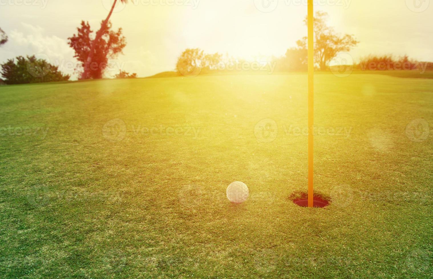 Golf ball near the hole in a grass field photo