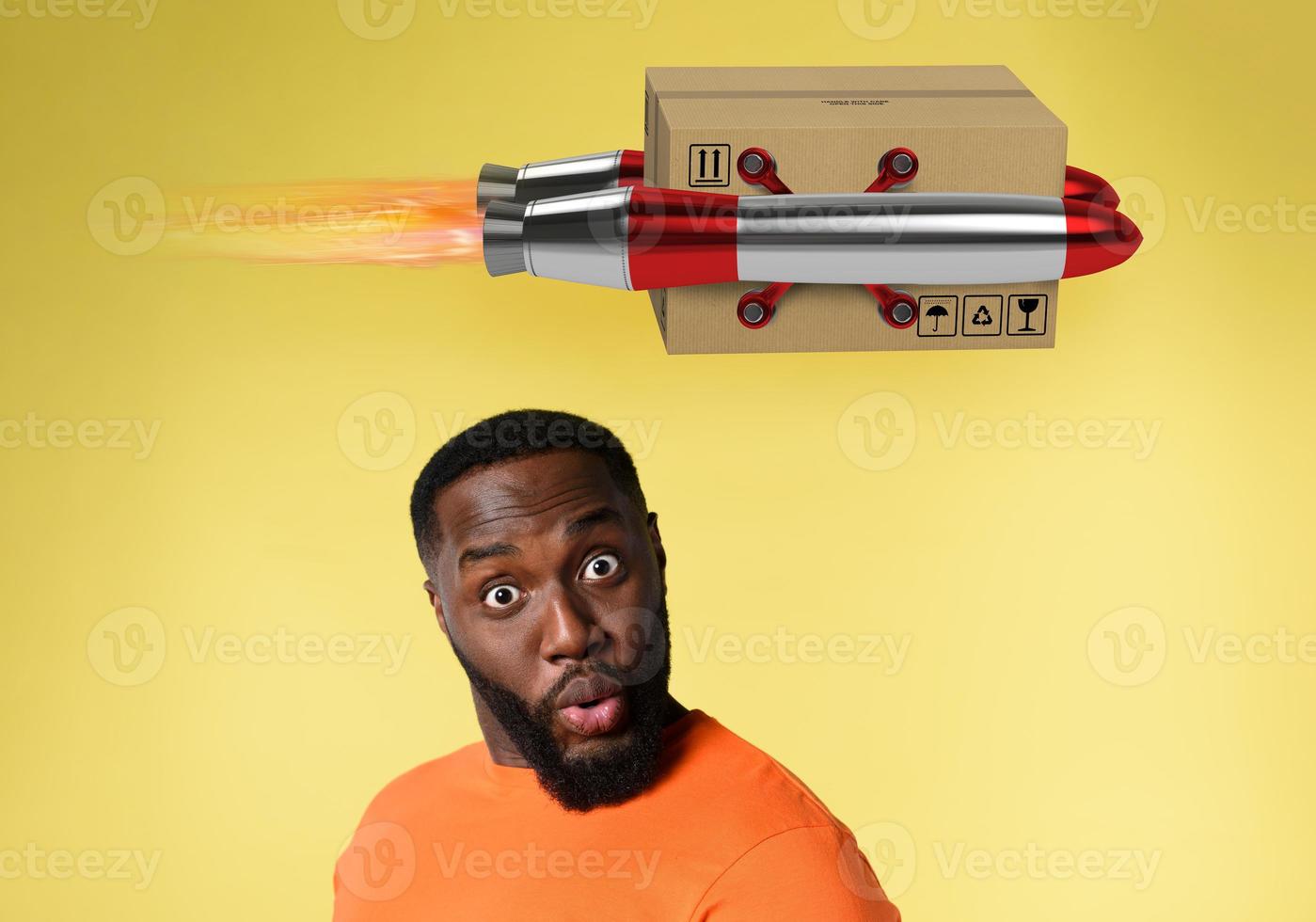 Black man with surprised and amazed expression. concept of express and priority shipment. yellow background photo