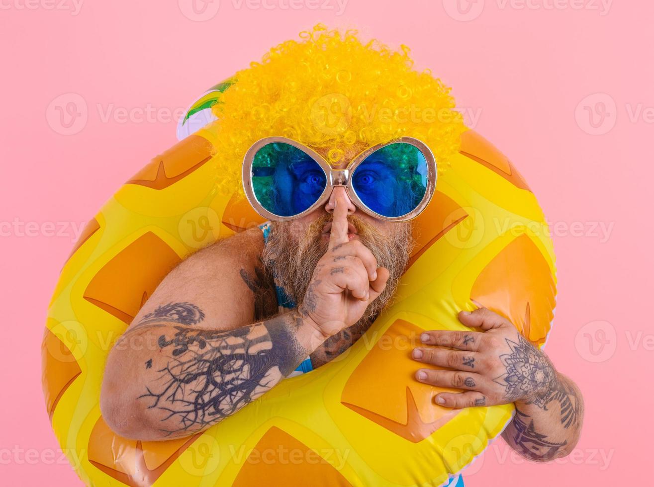 Fat man with wig in head is ready to swim with a donut lifesaver photo