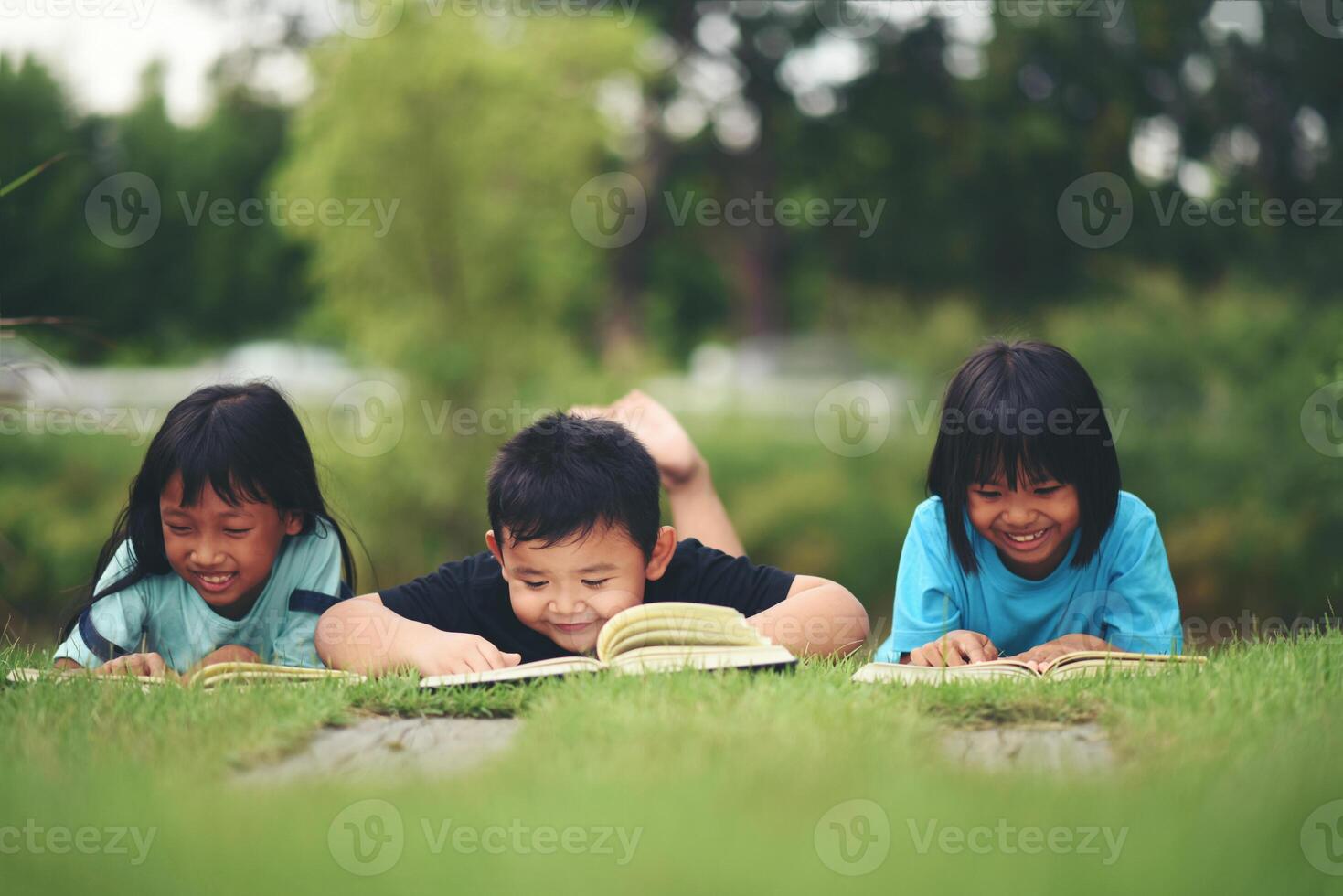 Group of children lying reading on grass field photo