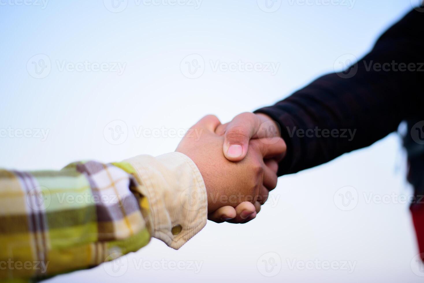 Close-up hand of Two male hikers helping each other climb up a mountain photo