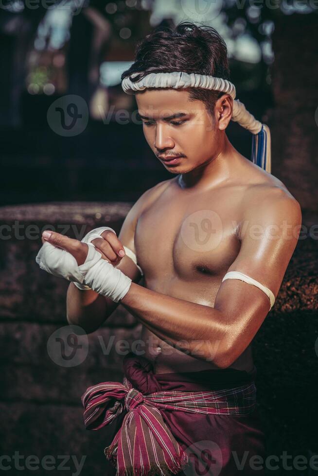 el boxeador se sentó en la piedra, ató la cinta alrededor de su mano, preparándose para pelear. foto