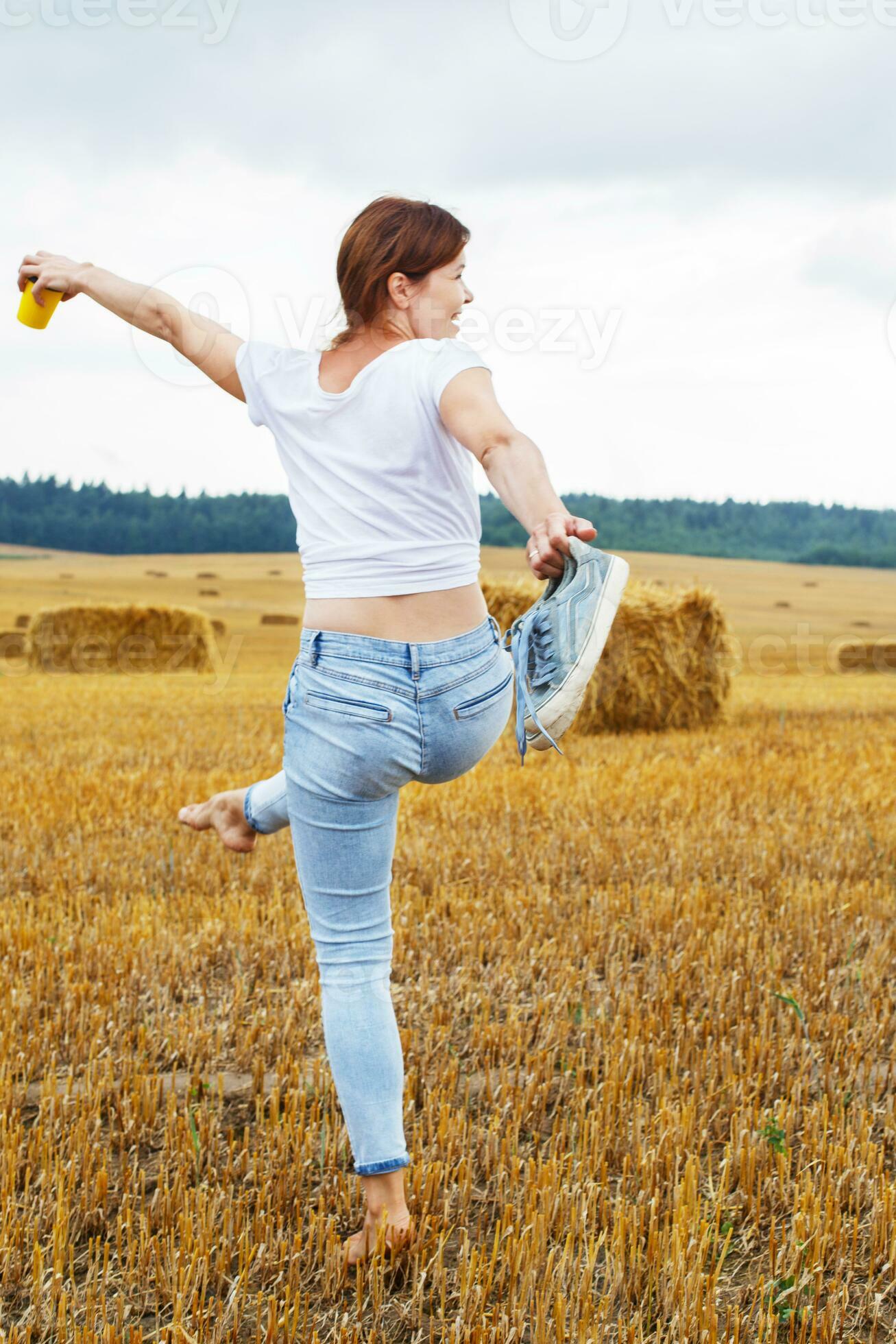 https://static.vecteezy.com/system/resources/previews/020/641/601/large_2x/barefoot-girl-with-sneakers-and-cardboard-cup-with-coffee-in-hand-walking-in-the-agricultural-field-photo.JPG