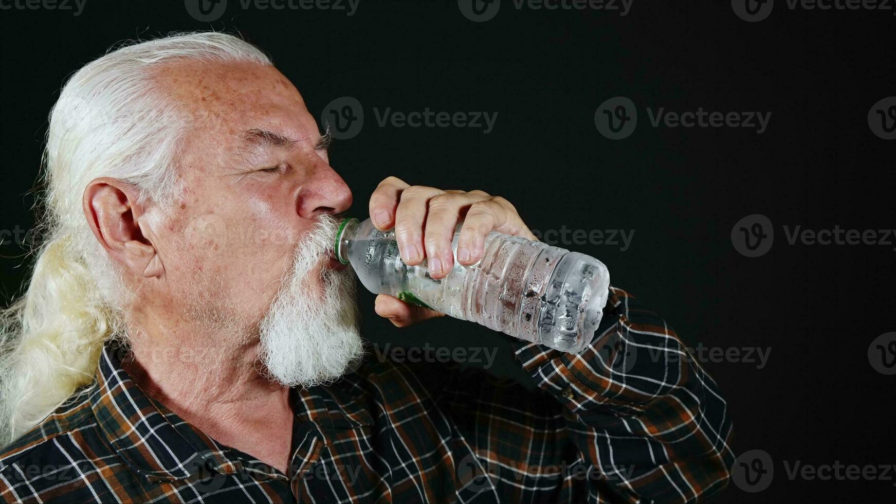 antiguo blanco peludo hombre es Bebiendo agua desde el plastico botella foto