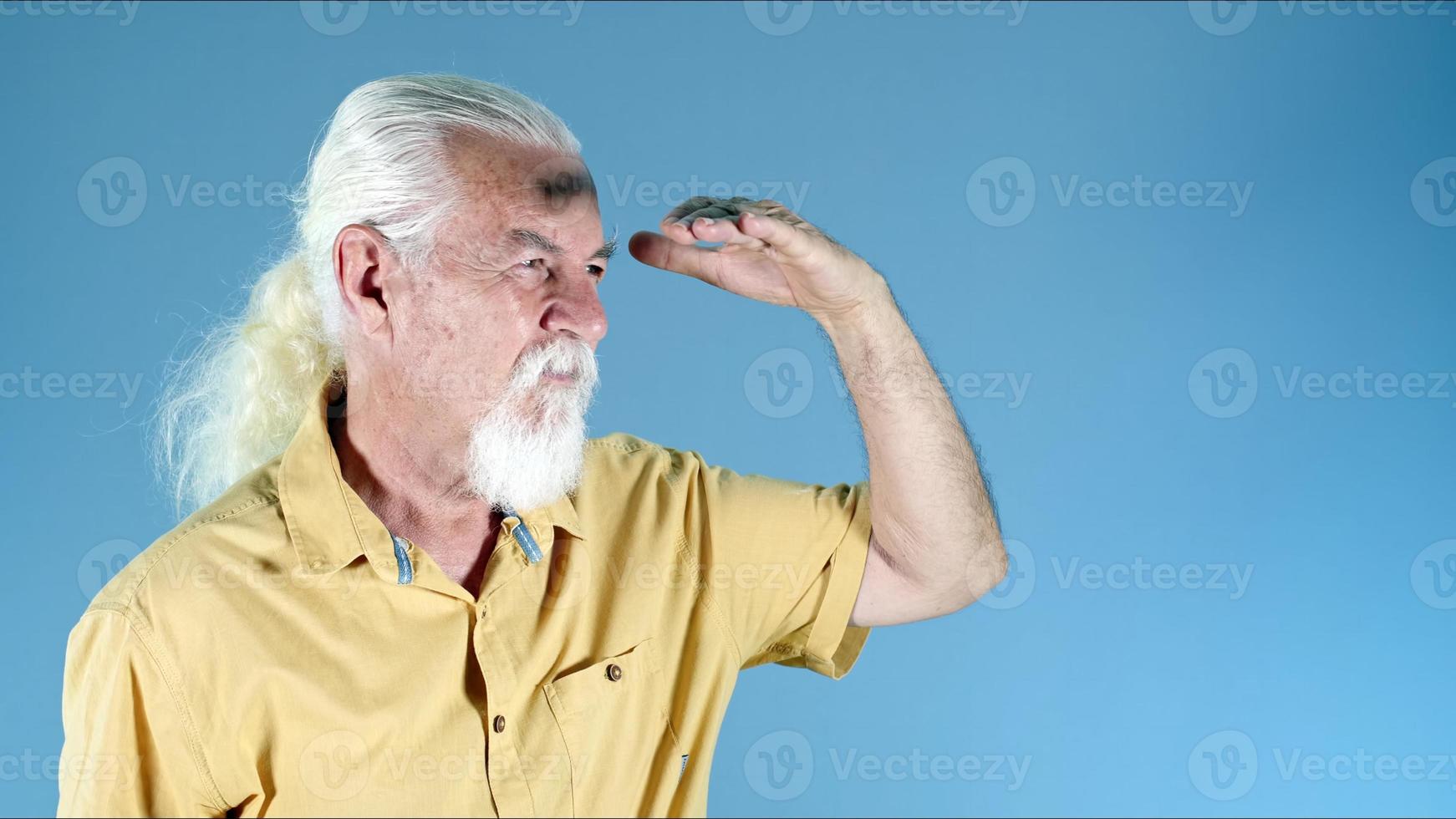 Old man shadows with his hand and looks photo