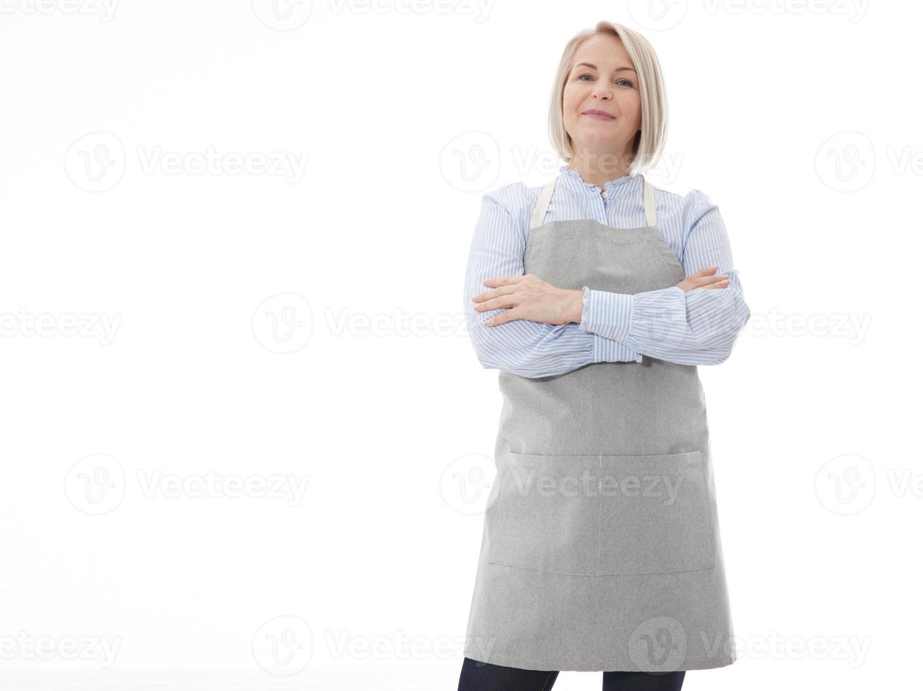 mujer en delantal. confidente bello mujer en delantal acuerdo brazos cruzado y sonriente mientras en pie en contra blanco antecedentes foto