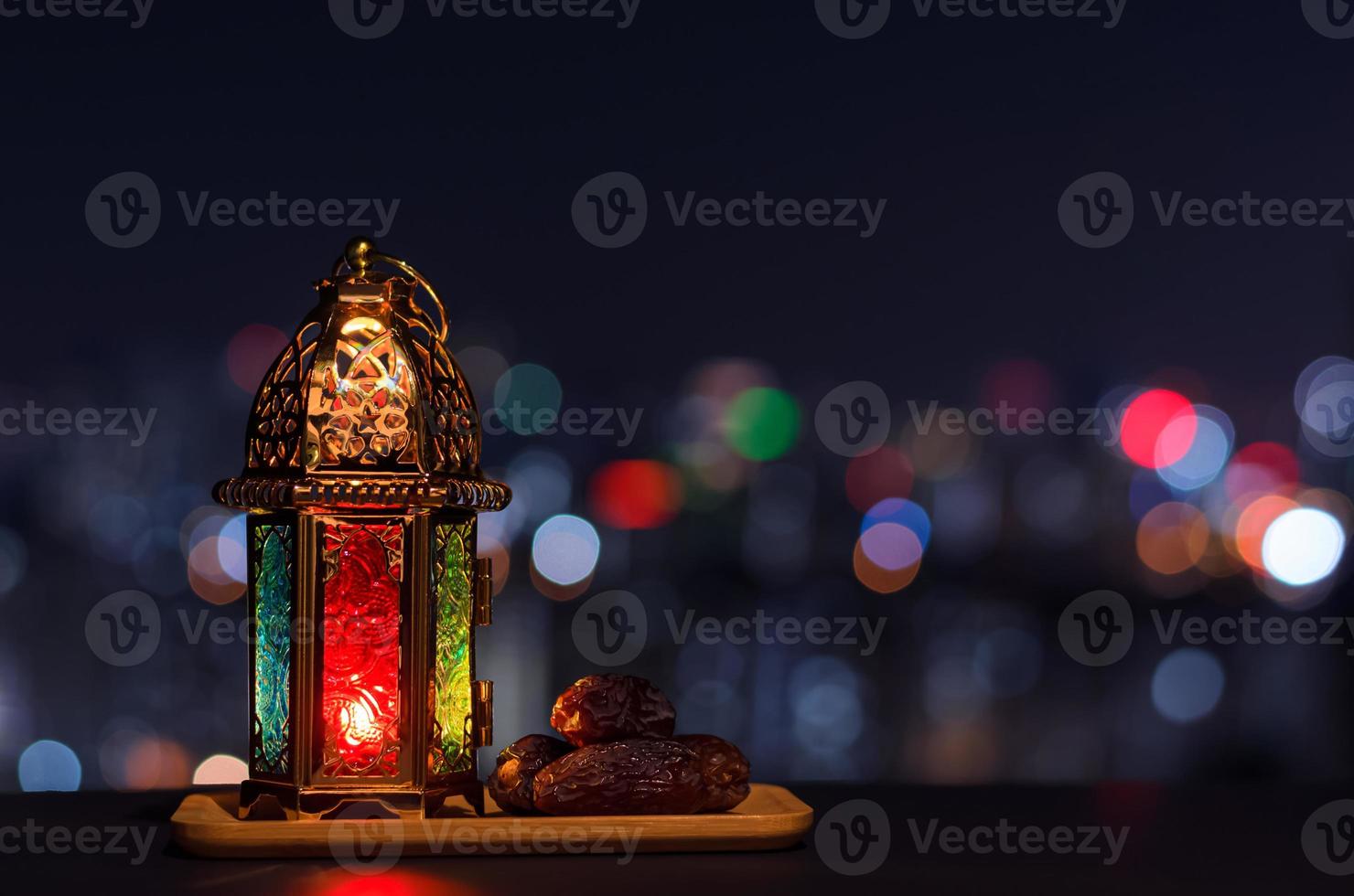 linterna y plato pequeño de dátiles con cielo nocturno y fondo claro de la ciudad para la fiesta musulmana del mes sagrado del ramadán kareem. foto