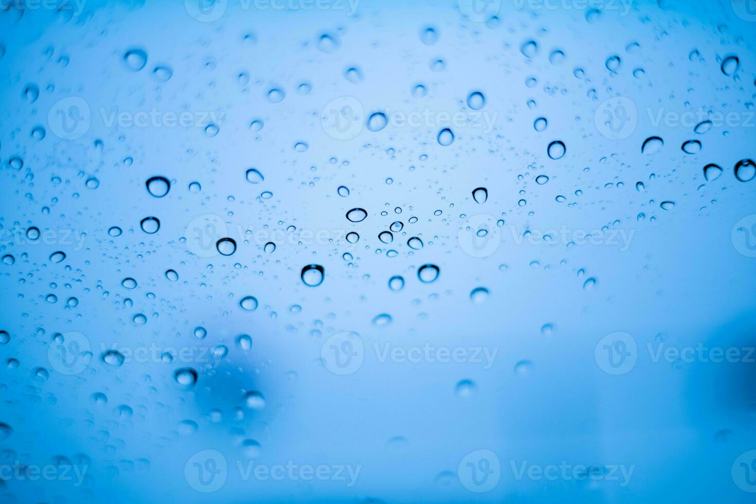 Blue water droplets and raindrops cling to the cool clear glass photo