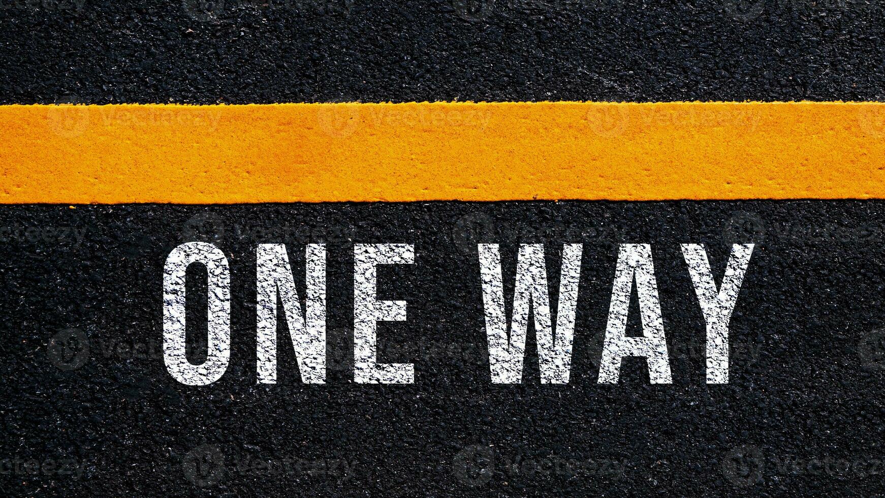 One way text written and yellow line on the road in middle of the asphalt road, One way word on street. photo