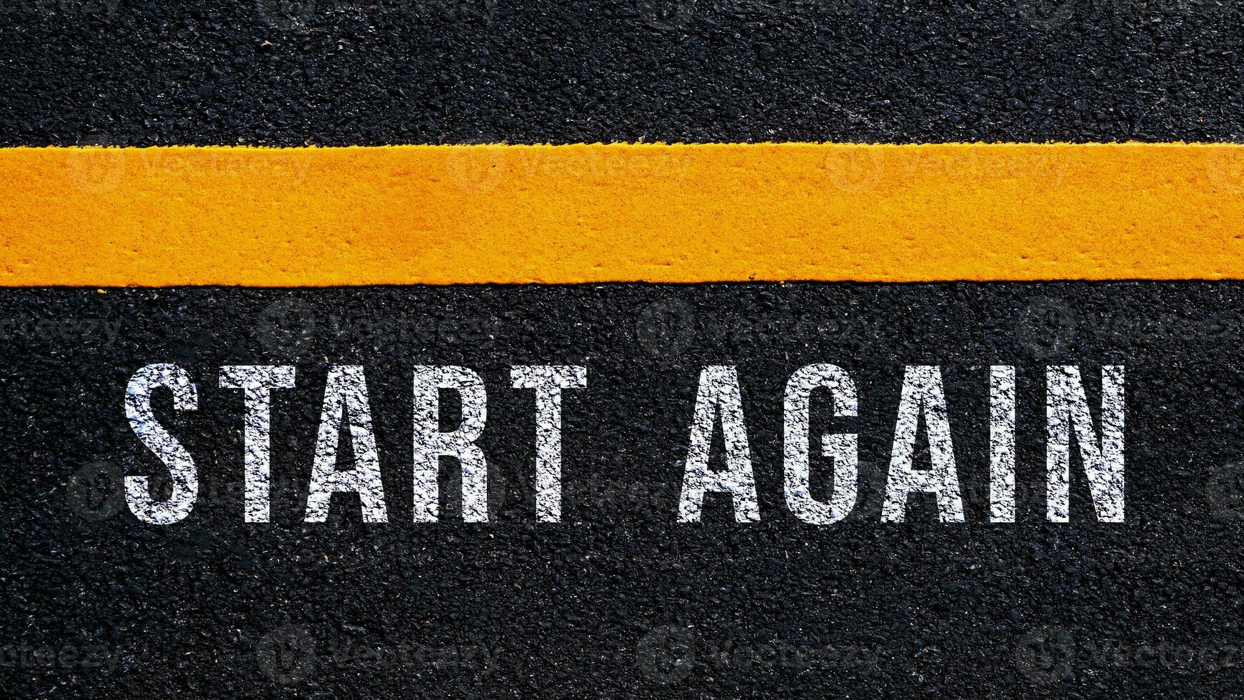 Start again text written and yellow line on the road in middle of the asphalt road, Start again word on street. photo