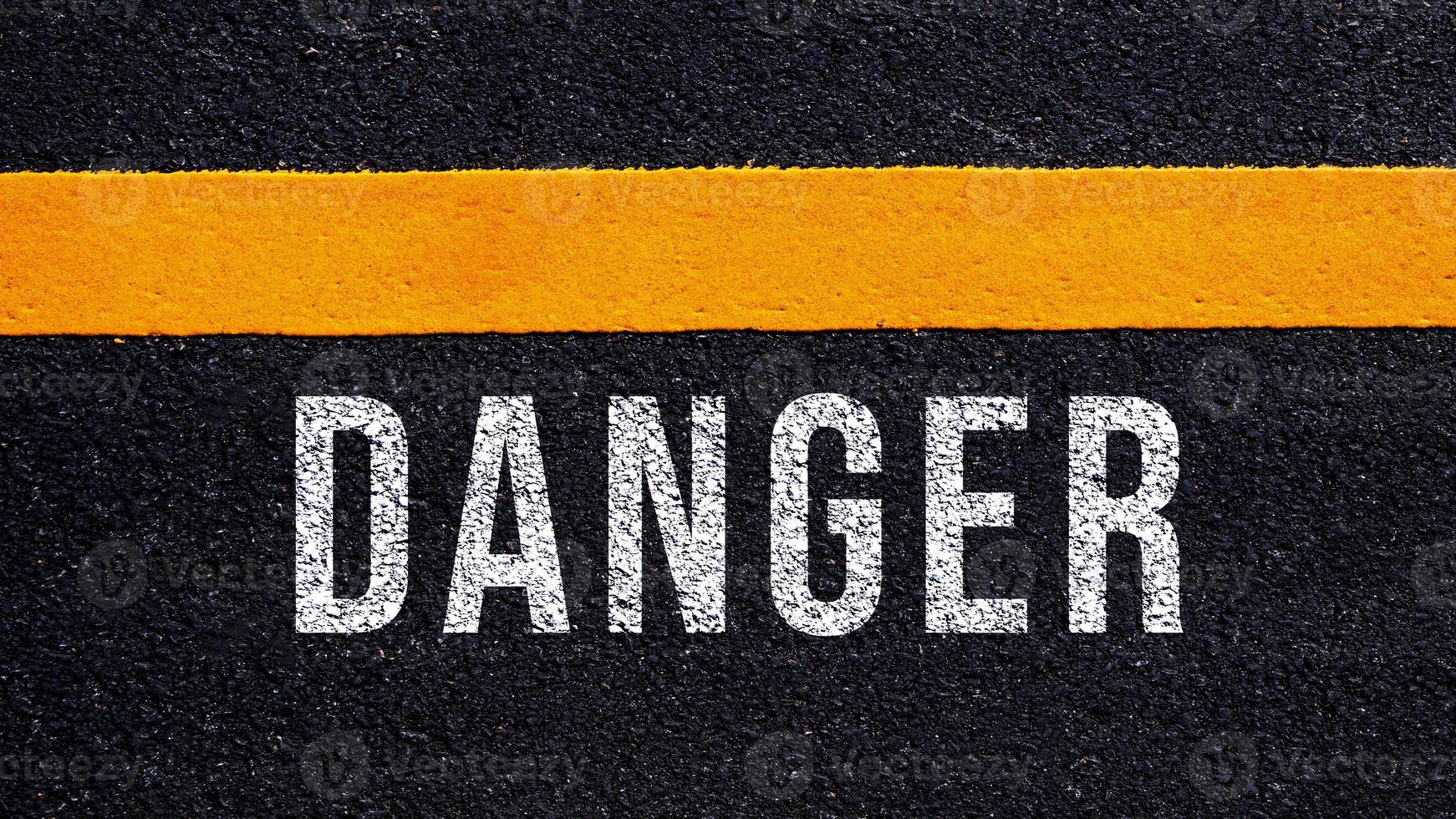 Danger written and yellow line on the road in middle of the asphalt road, Danger word on street. photo