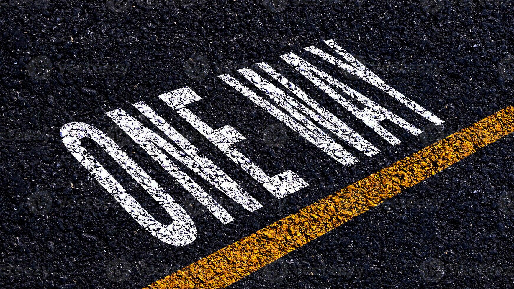 One way text written and yellow line on the road in middle of the asphalt road, One way word on street. photo