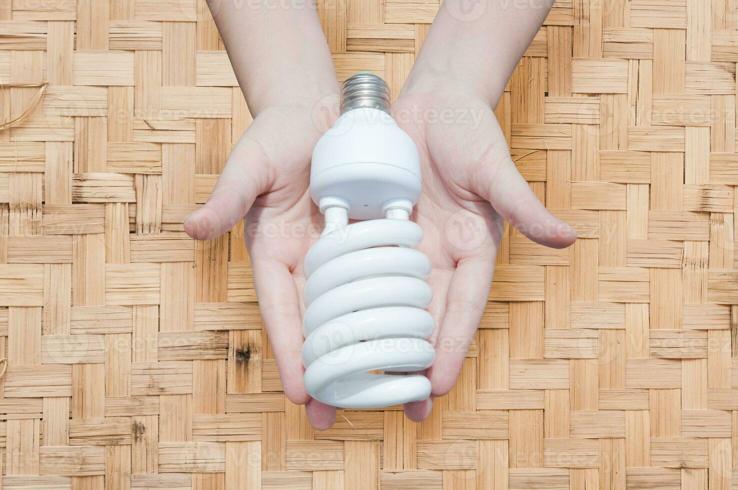 Energy saving concept, Woman hand holding light bulb on bamboo weave background,Ideas light bulb in the hand photo