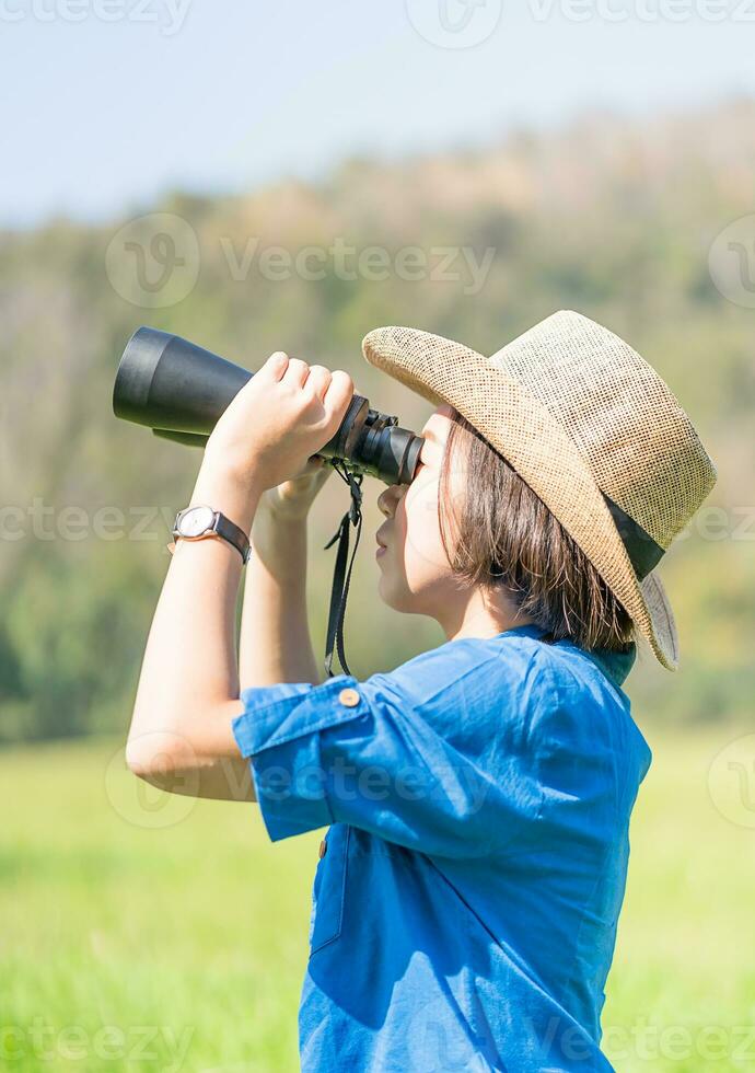 Woman wear hat and hold binocular in grass field photo