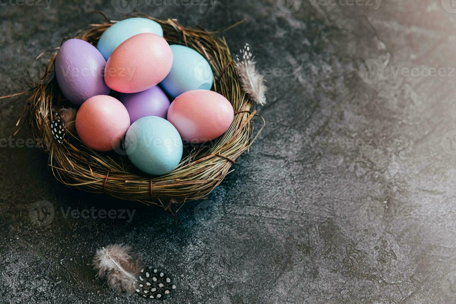 Happy Easter concept. Preparation for holiday. Colorful pastel decorated easter eggs in nest on grunge scratched dark black shale background. Simple minimalism flat lay top view copy space. photo